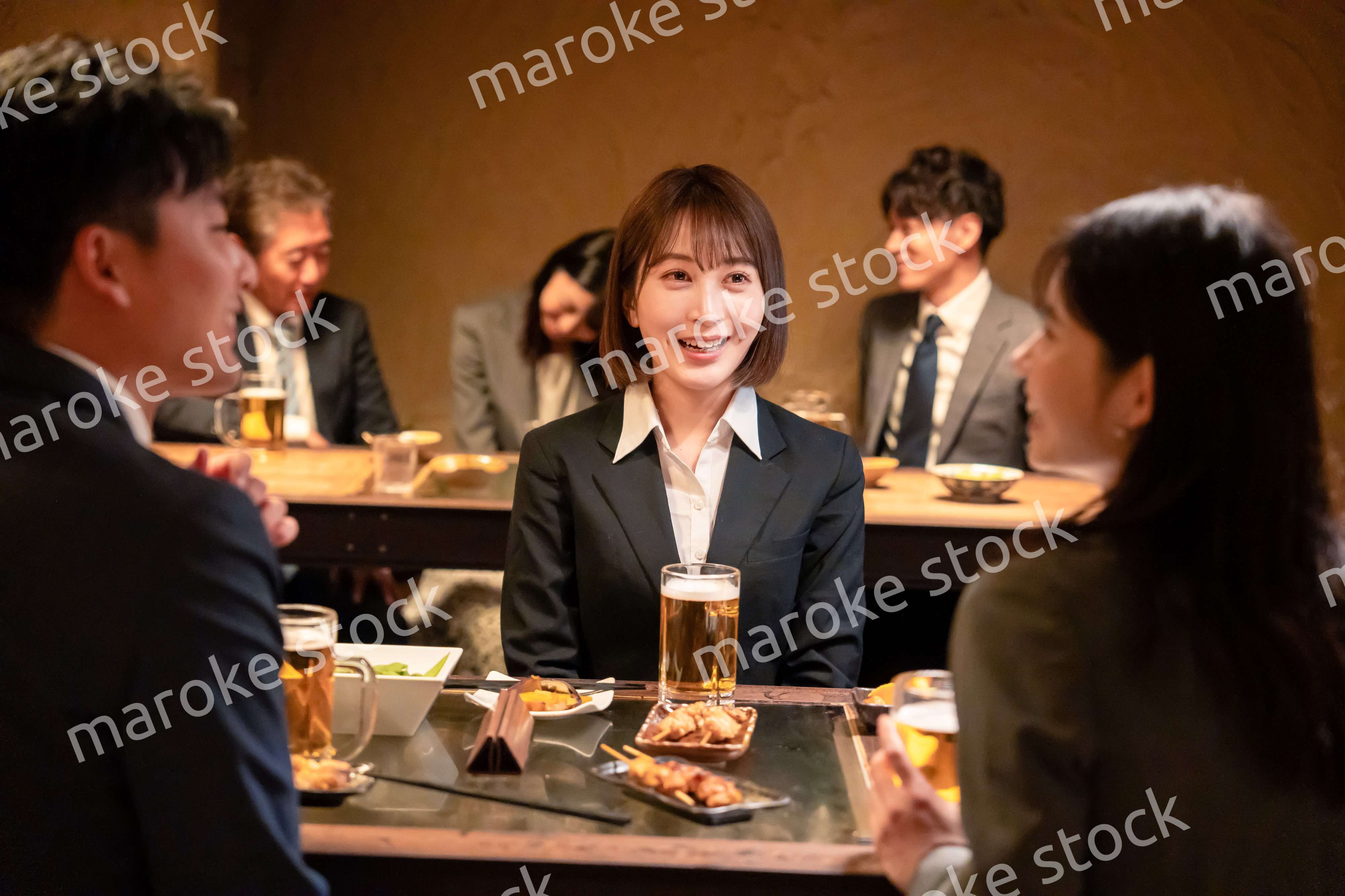 居酒屋で先輩社員とお酒を飲む新入社員