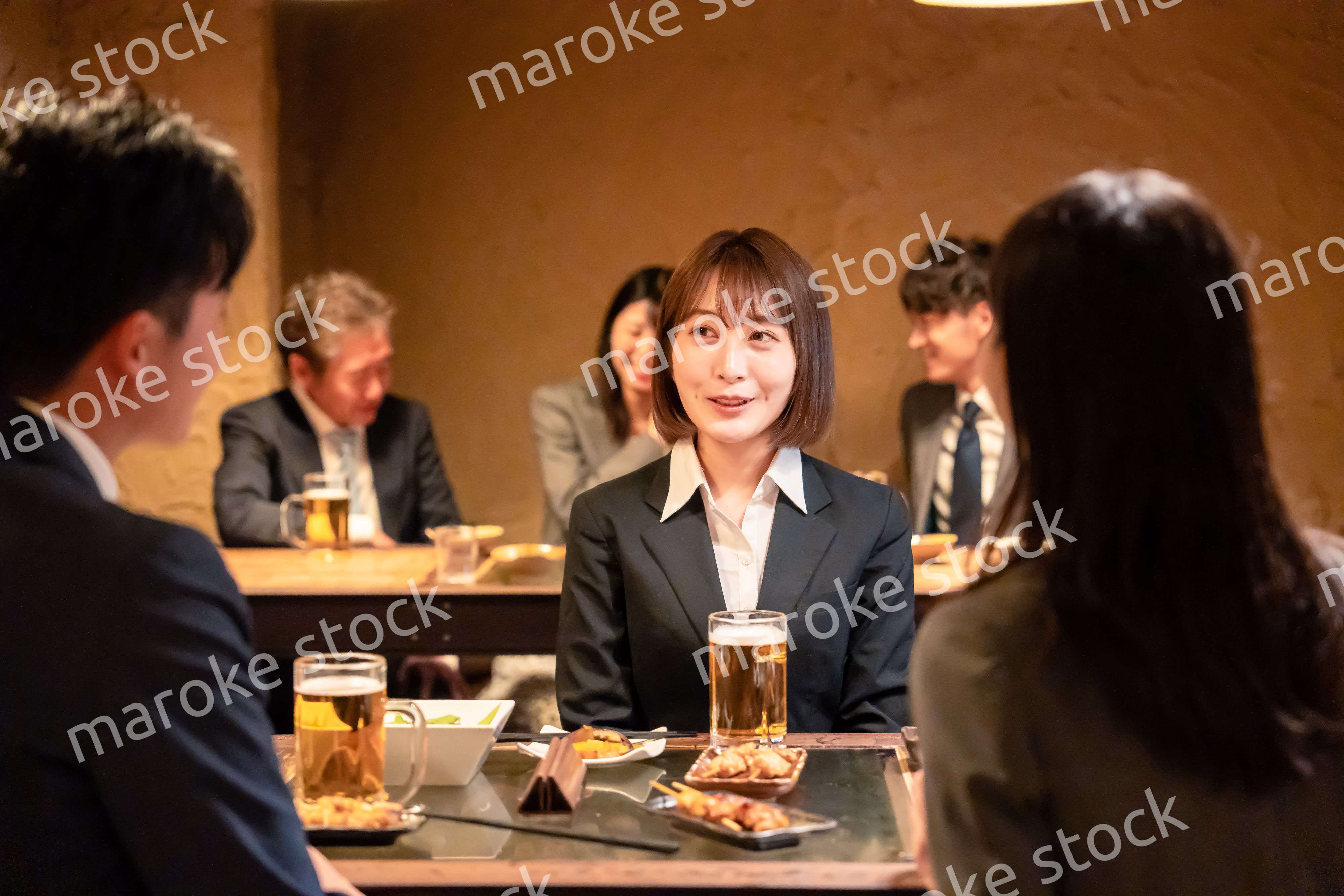 居酒屋で先輩社員とお酒を飲む新入社員