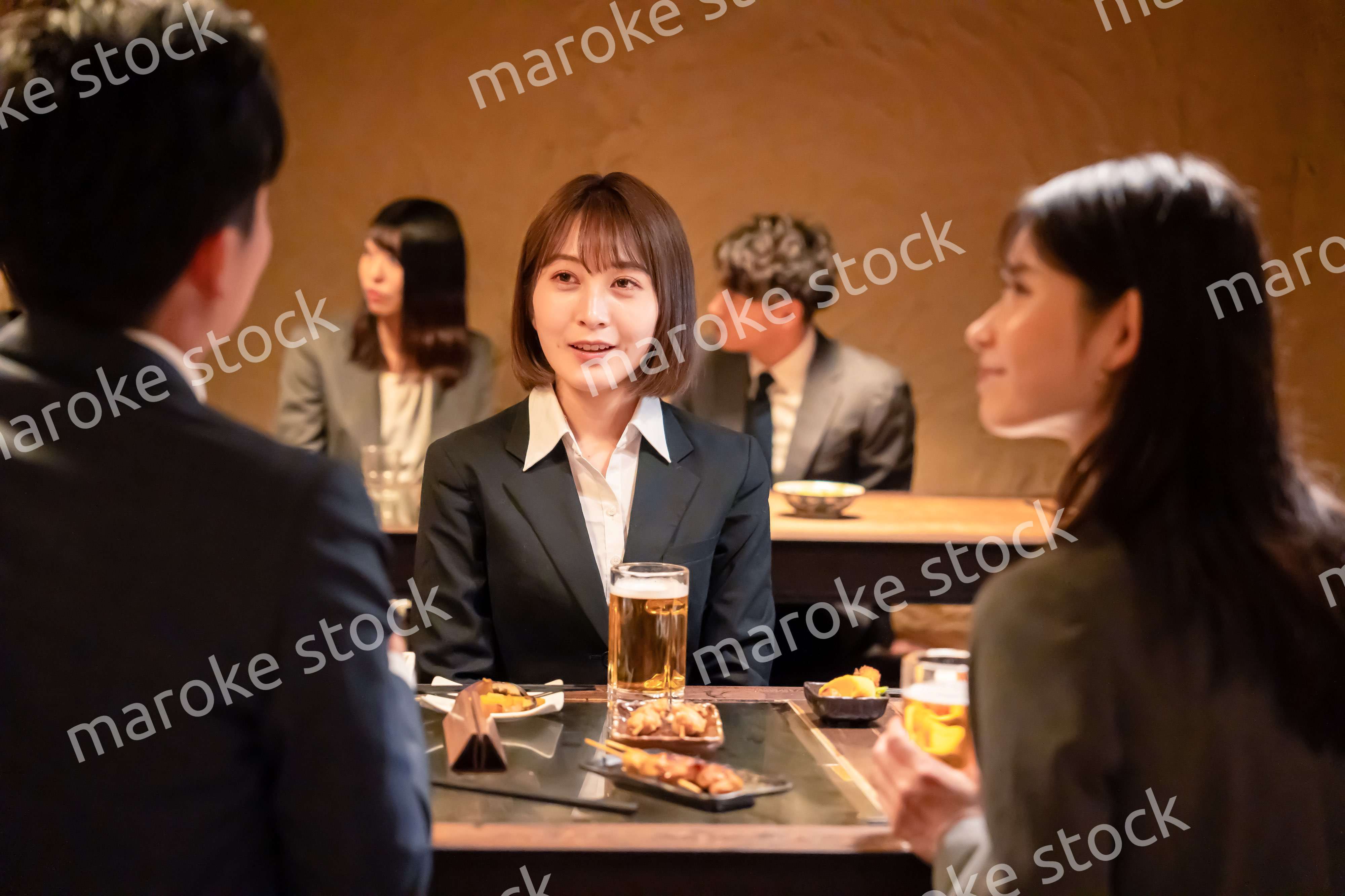 居酒屋で先輩社員とお酒を飲む新入社員