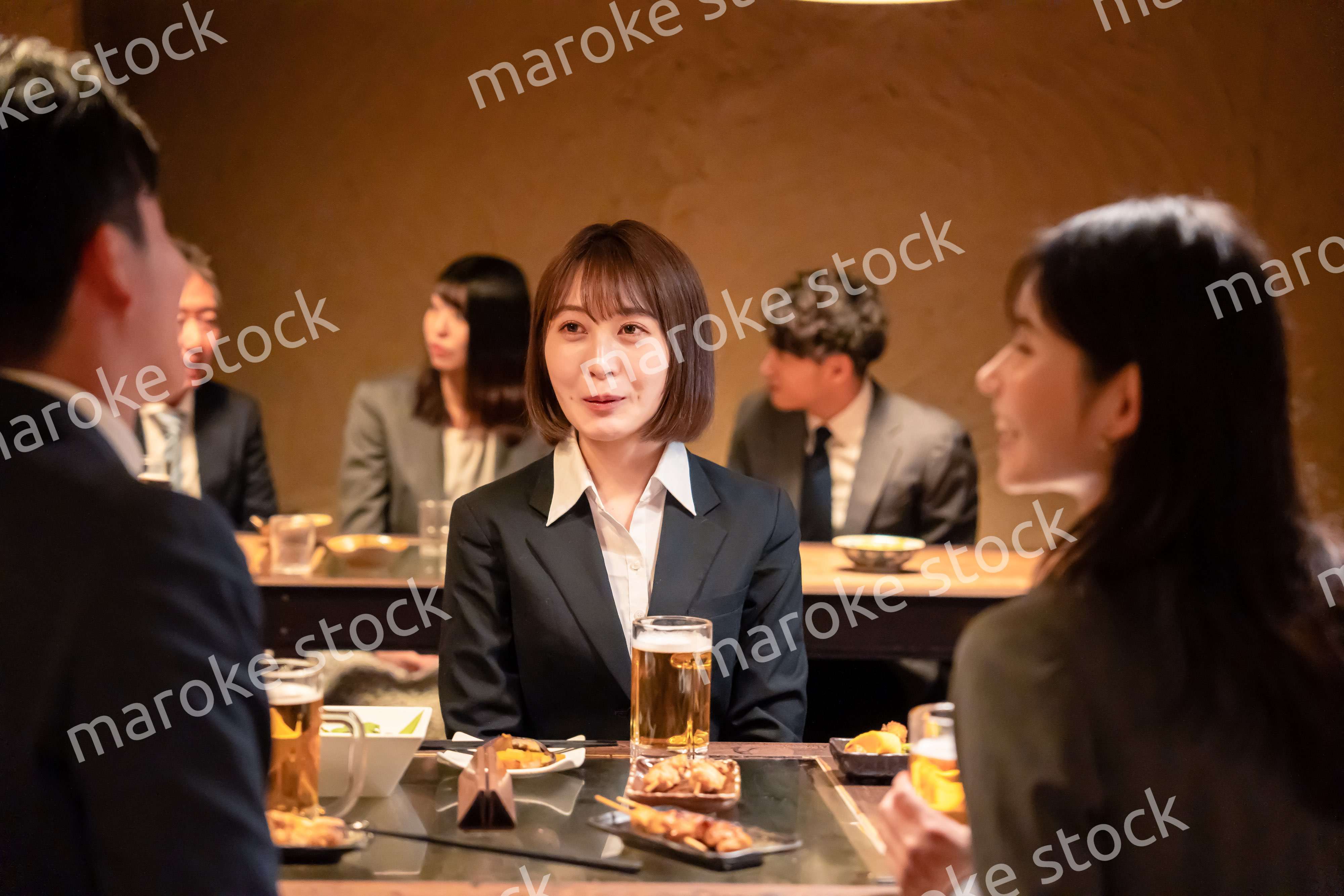 居酒屋で先輩社員とお酒を飲む新入社員