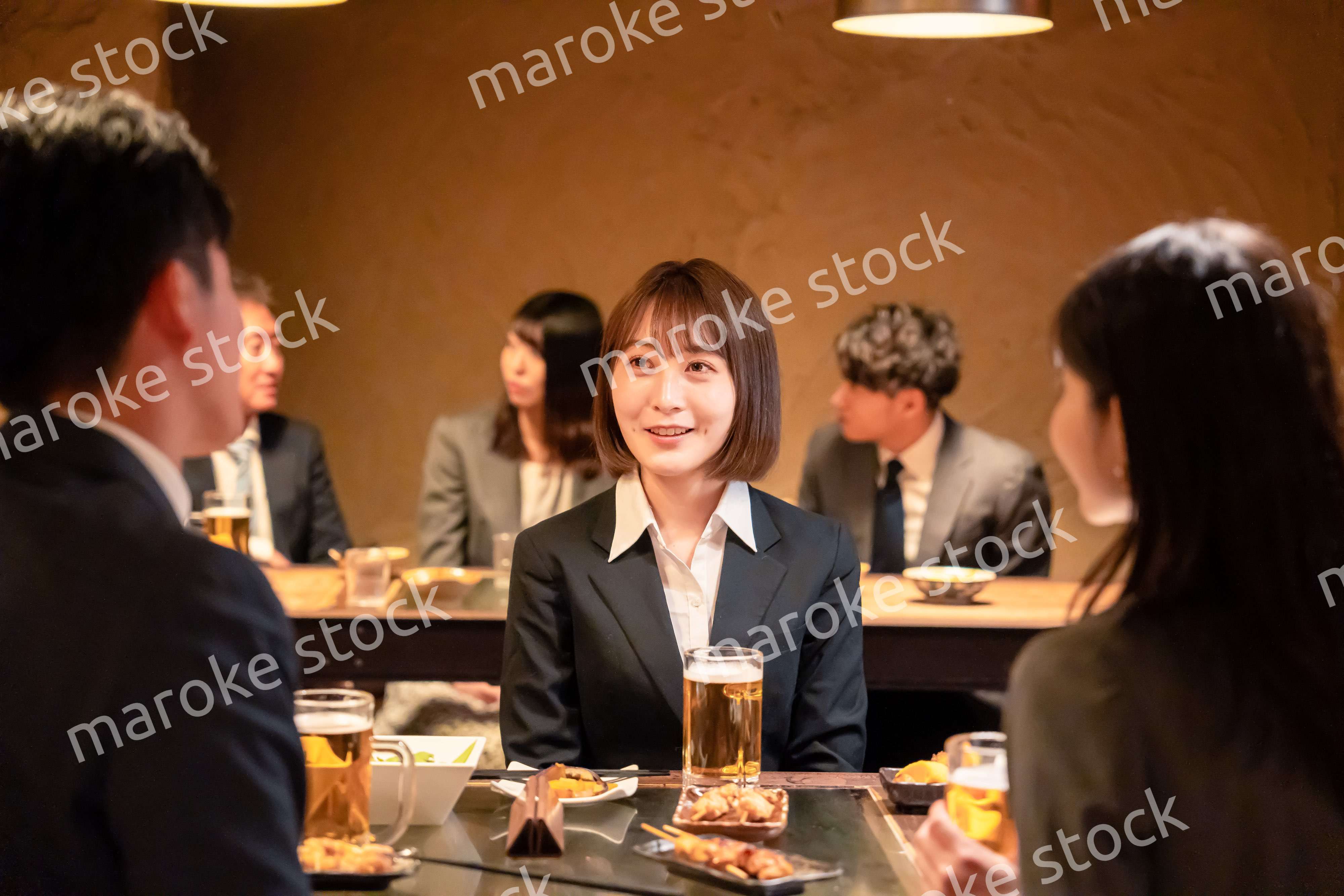 居酒屋で先輩社員とお酒を飲む新入社員