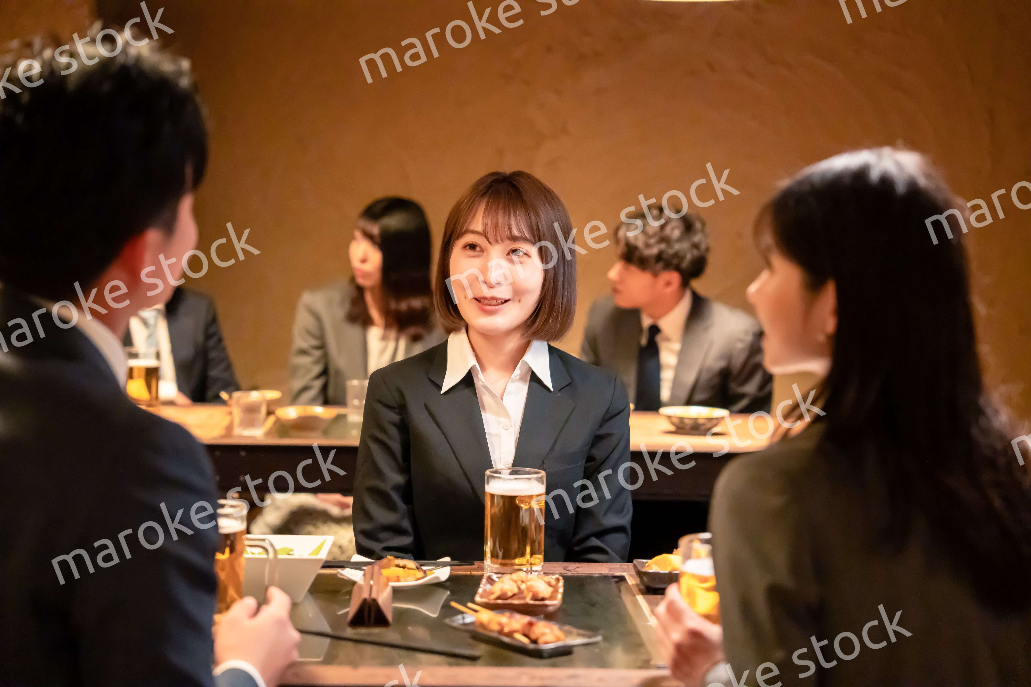 居酒屋で先輩社員とお酒を飲む新入社員