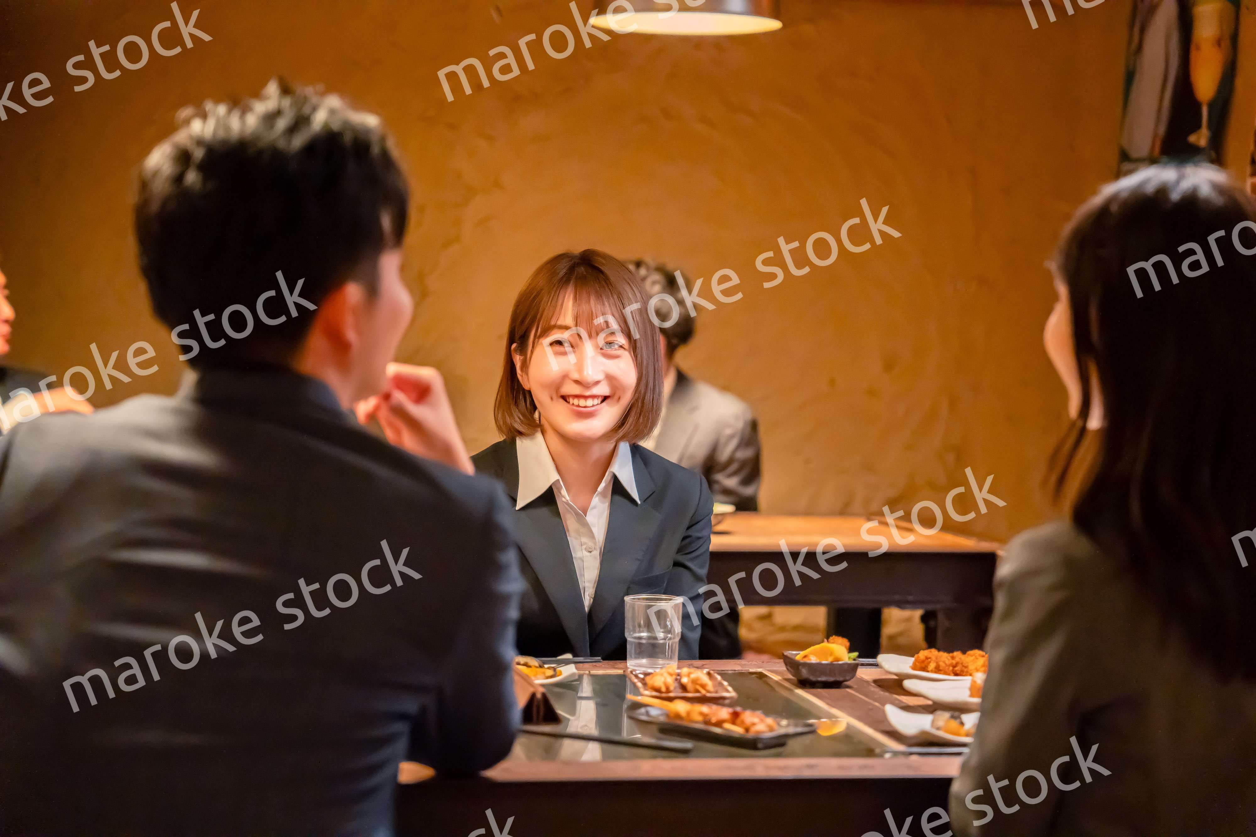 先輩社員と居酒屋で話をするフレッシュな女性