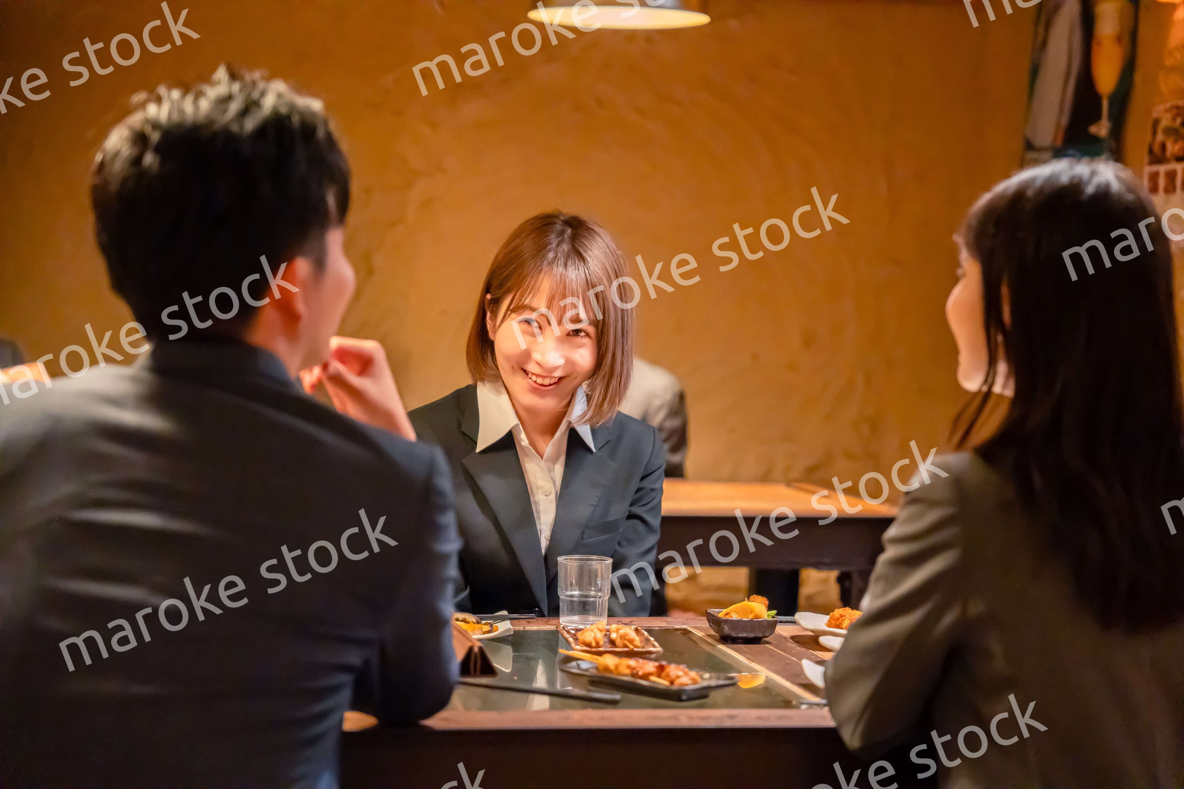 先輩社員と居酒屋で話をするフレッシュな女性