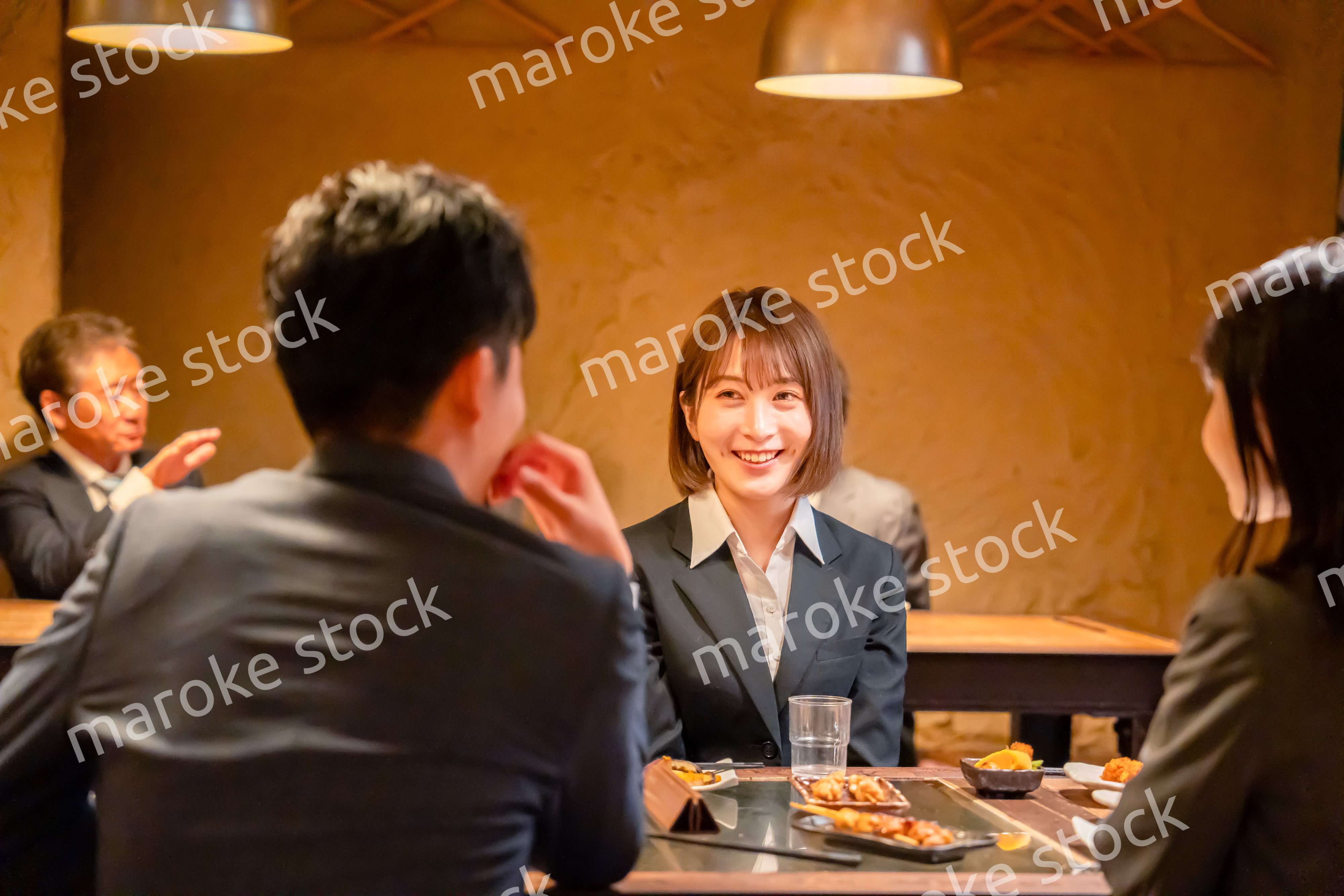 先輩社員と居酒屋で話をするフレッシュな女性