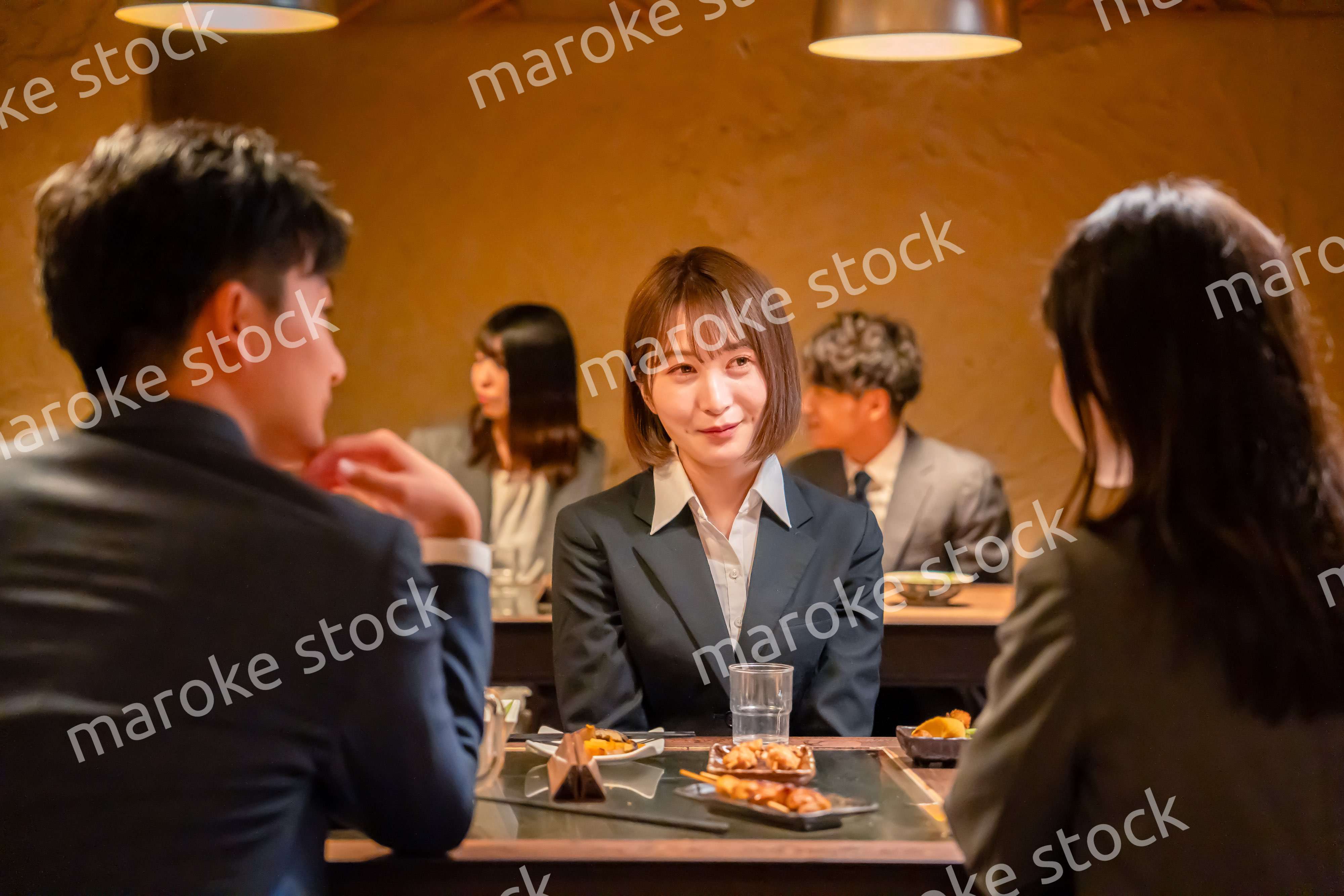 先輩社員と居酒屋で話をするフレッシュな女性