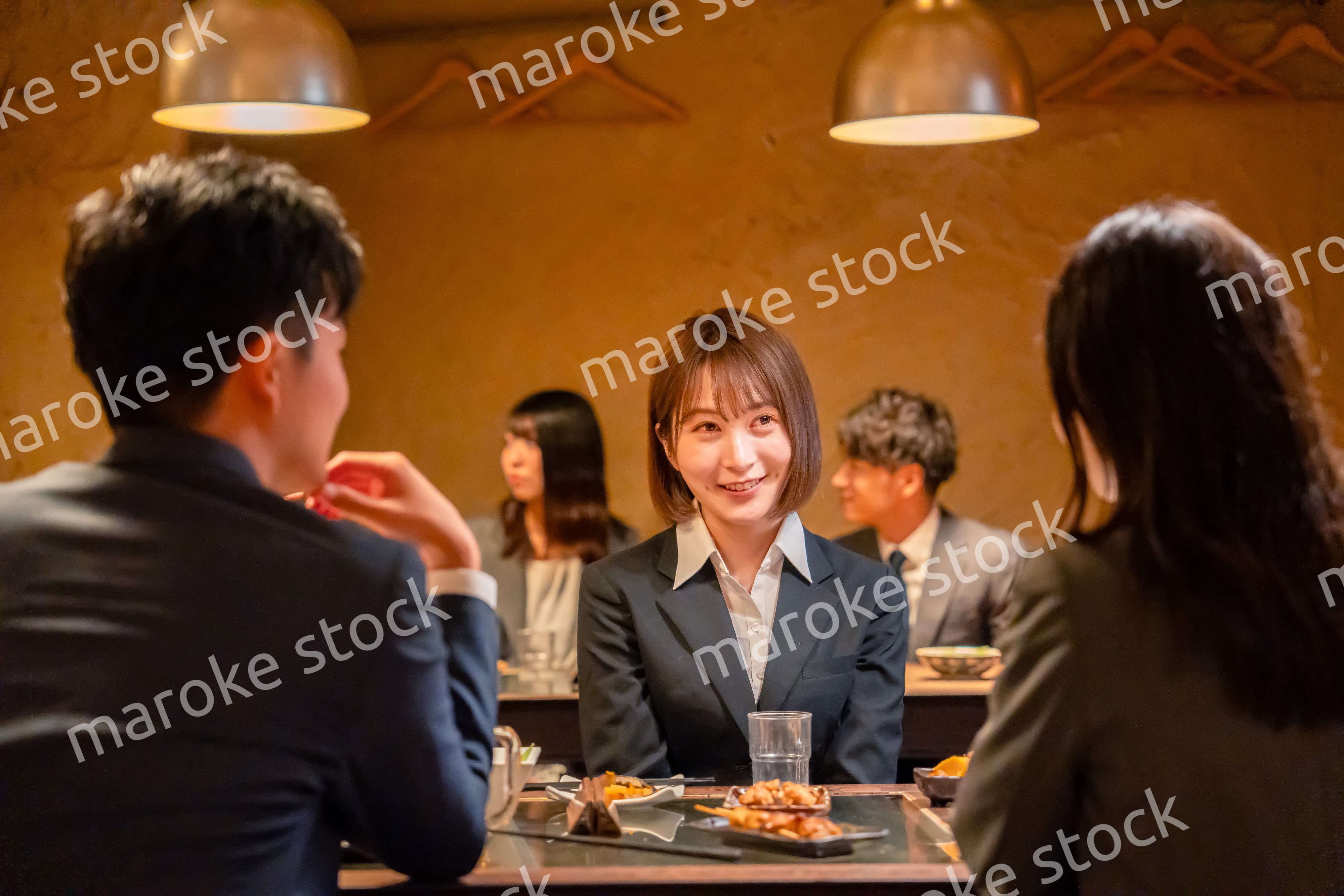 先輩社員と居酒屋で話をするフレッシュな女性