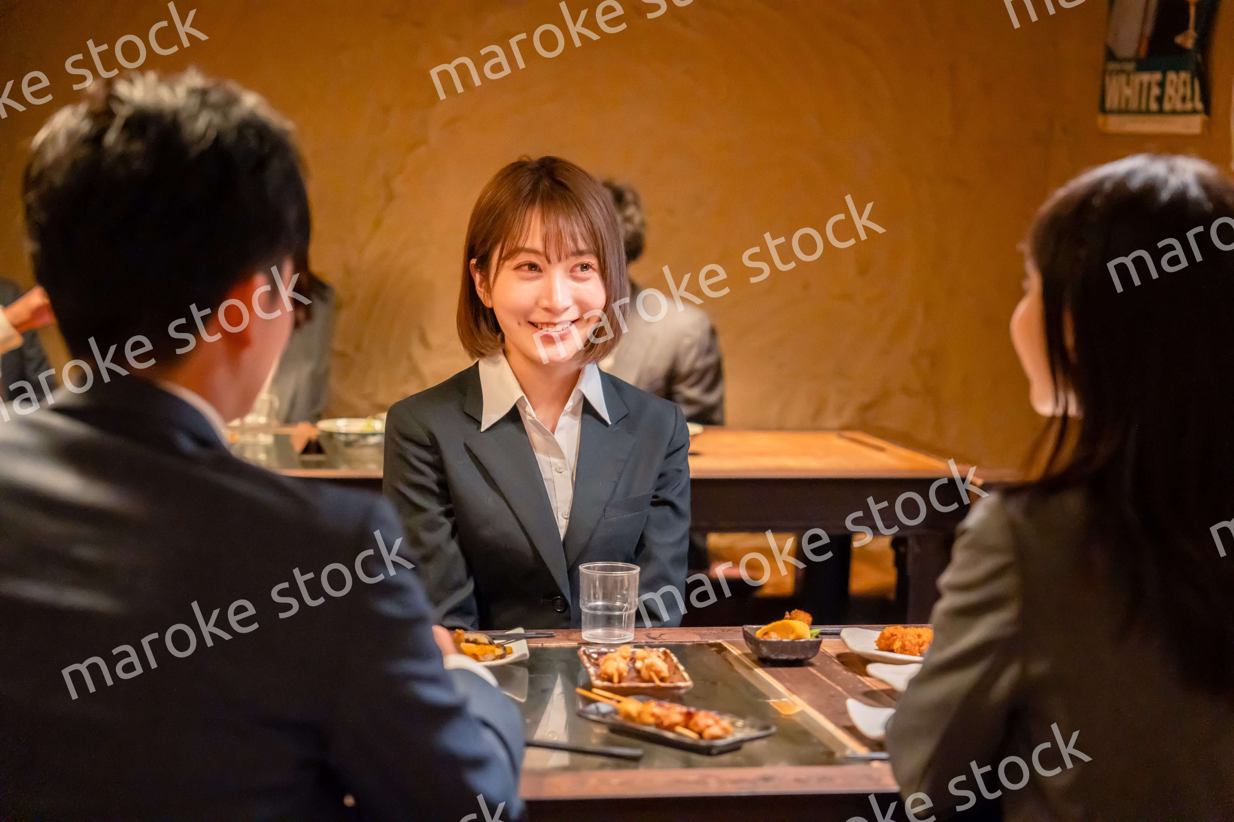 先輩社員と居酒屋で話をするフレッシュな女性