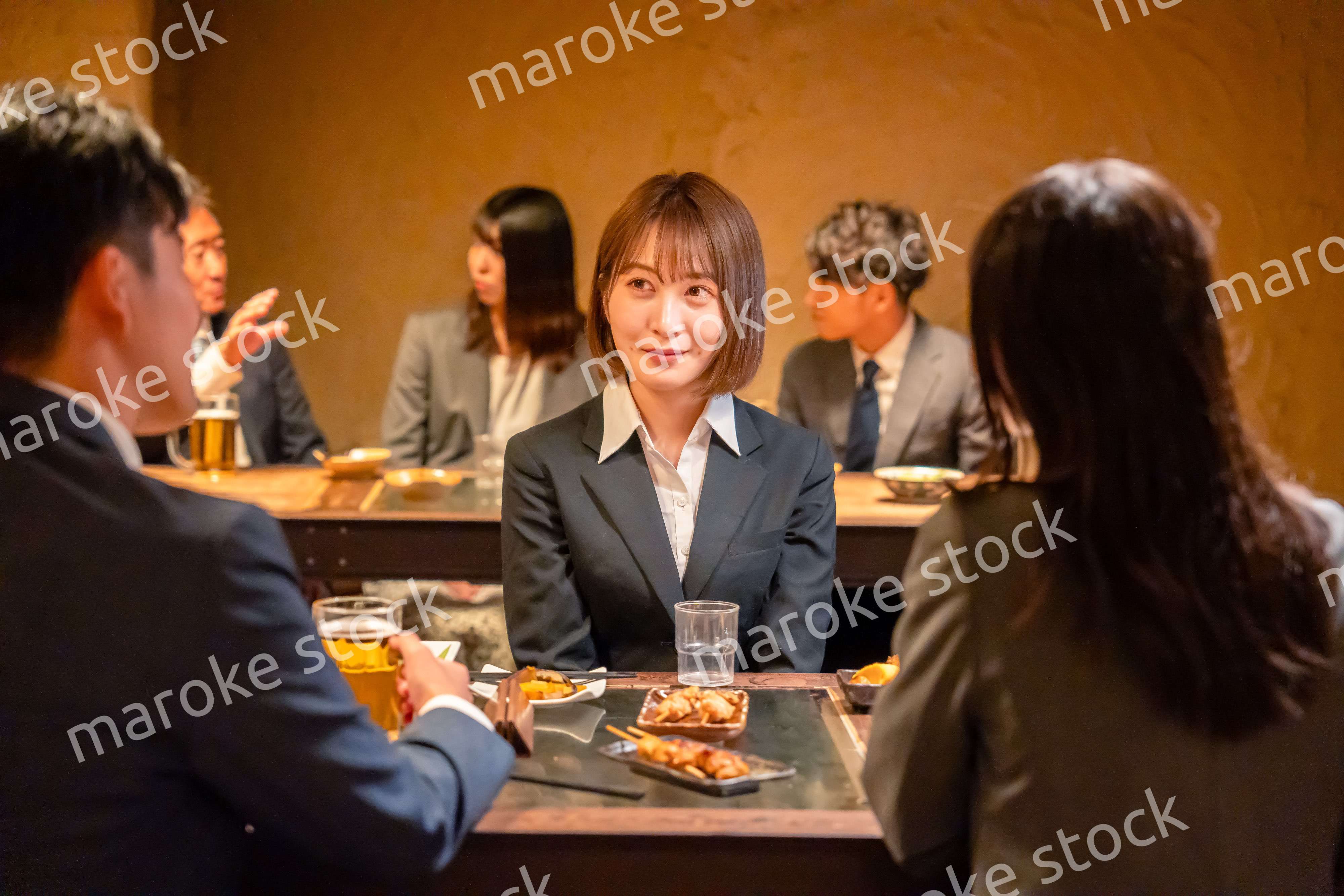 先輩社員と居酒屋で話をするフレッシュな女性