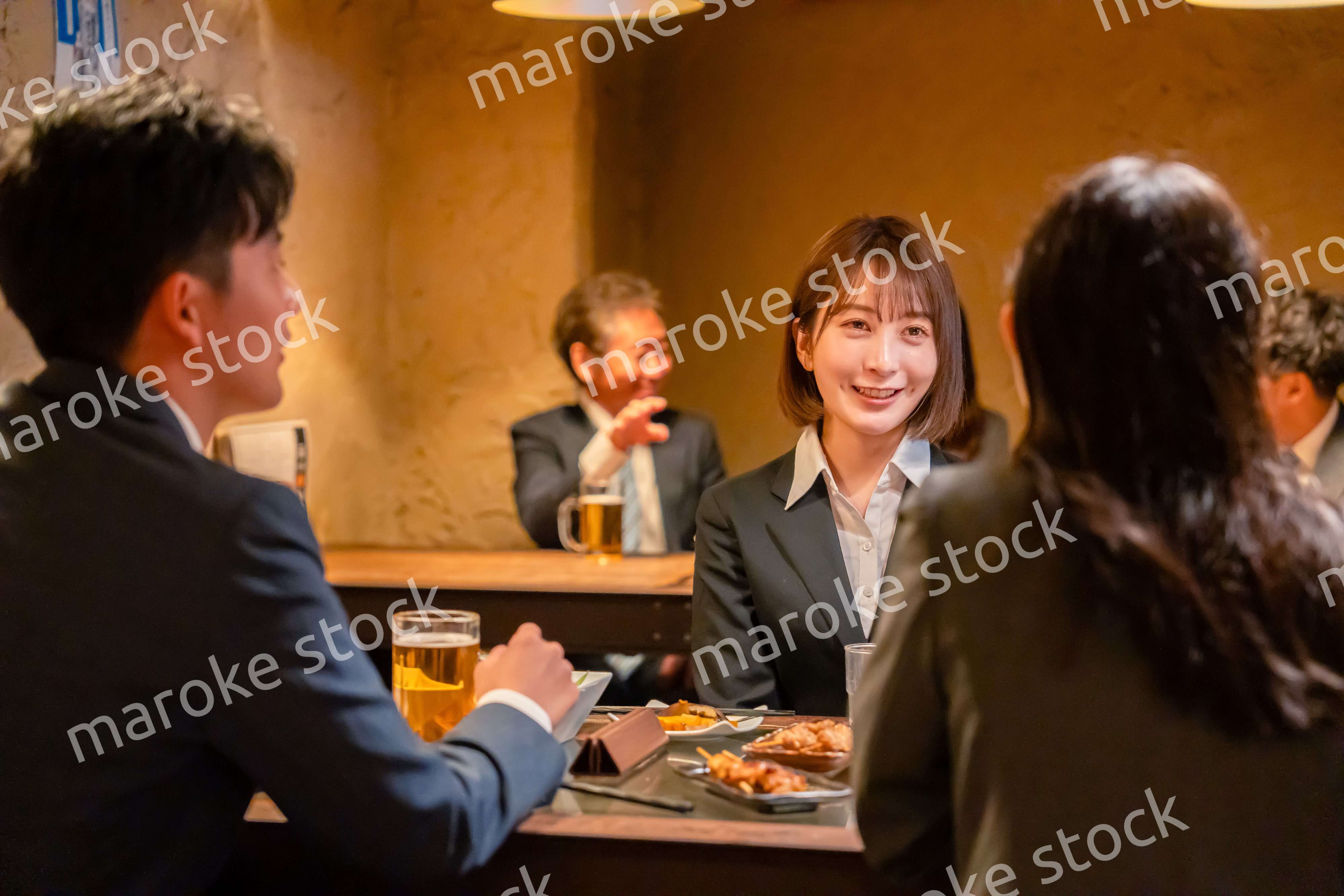 先輩社員と居酒屋で話をするフレッシュな女性