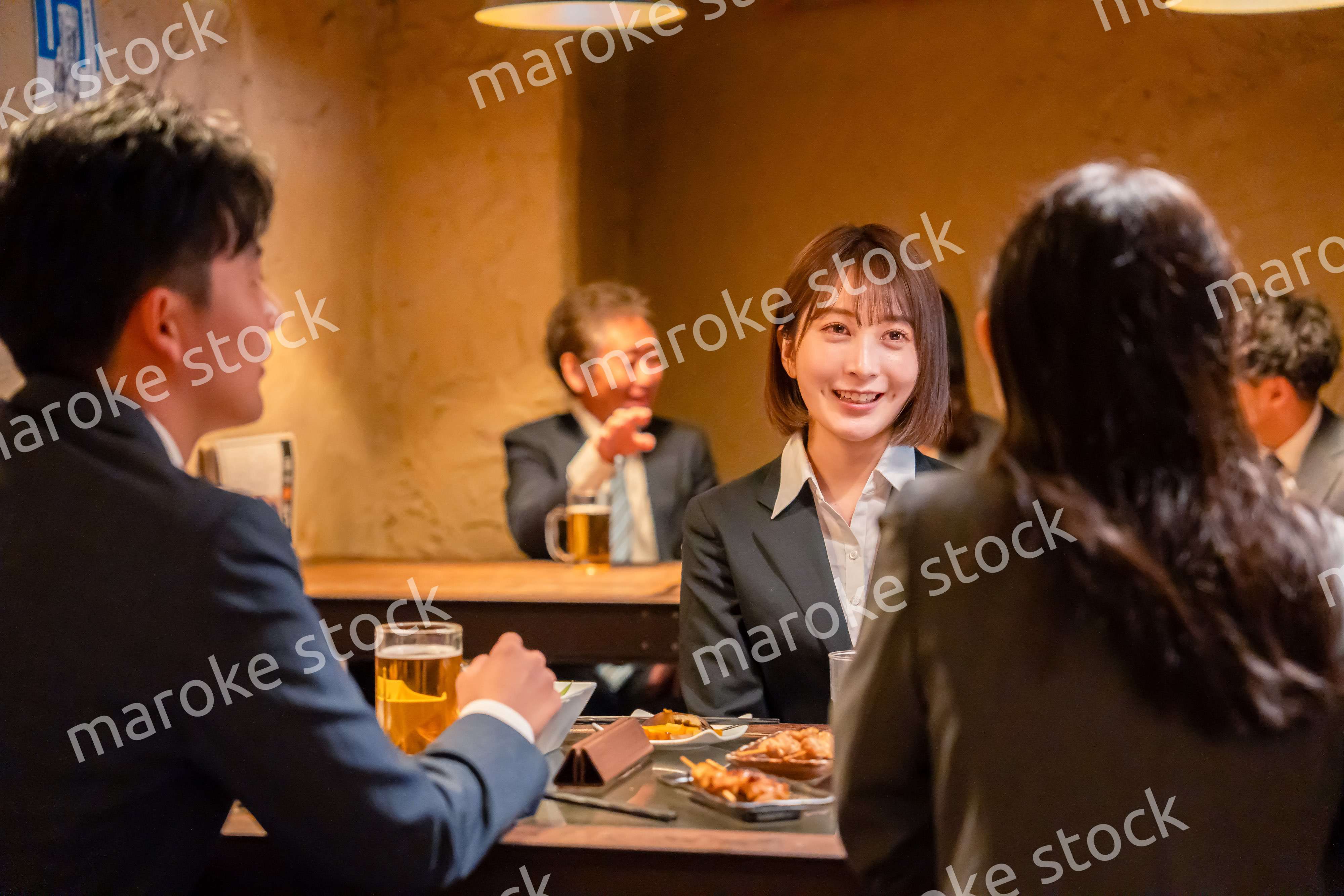 先輩社員と居酒屋で話をするフレッシュな女性