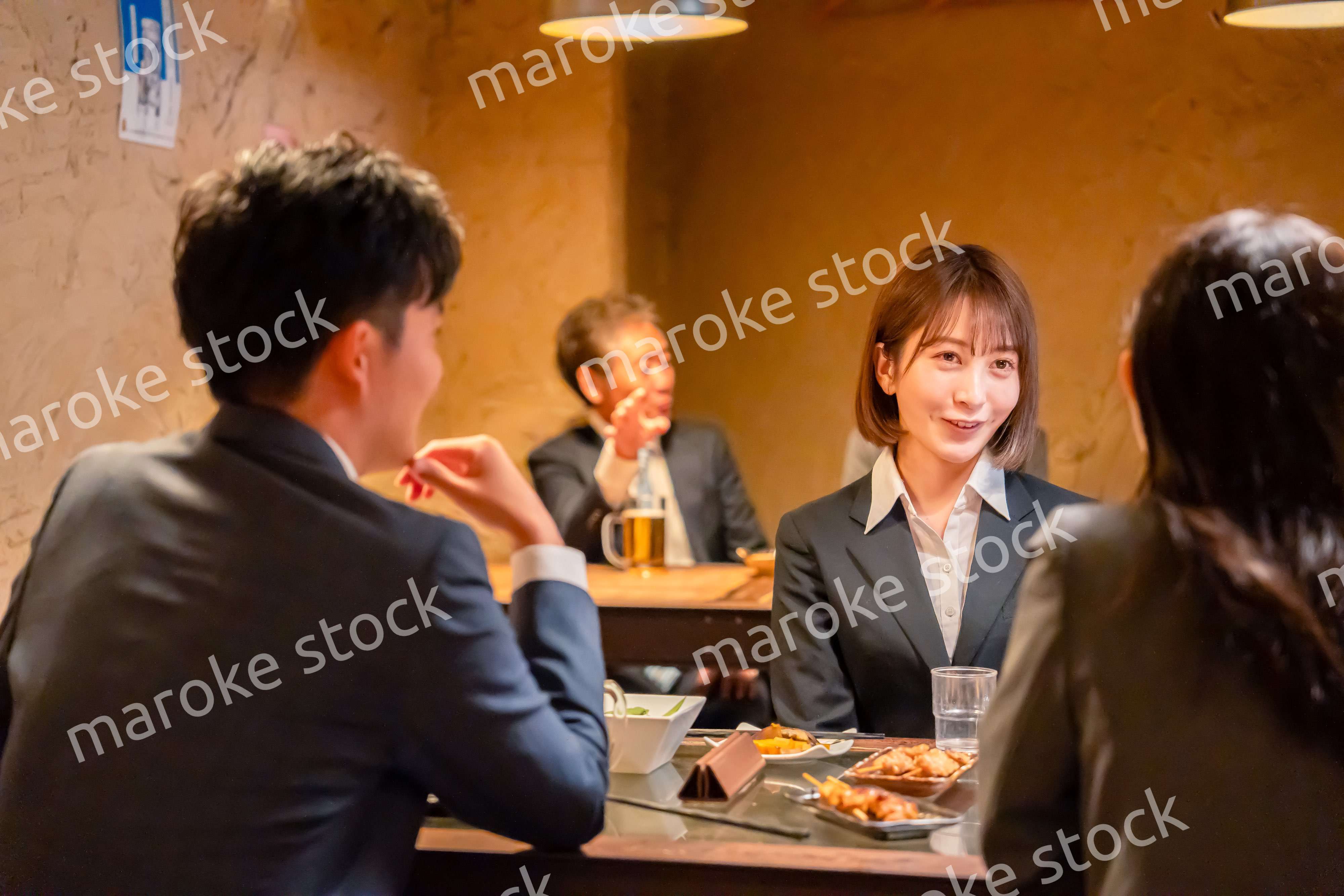 先輩社員と居酒屋で話をするフレッシュな女性