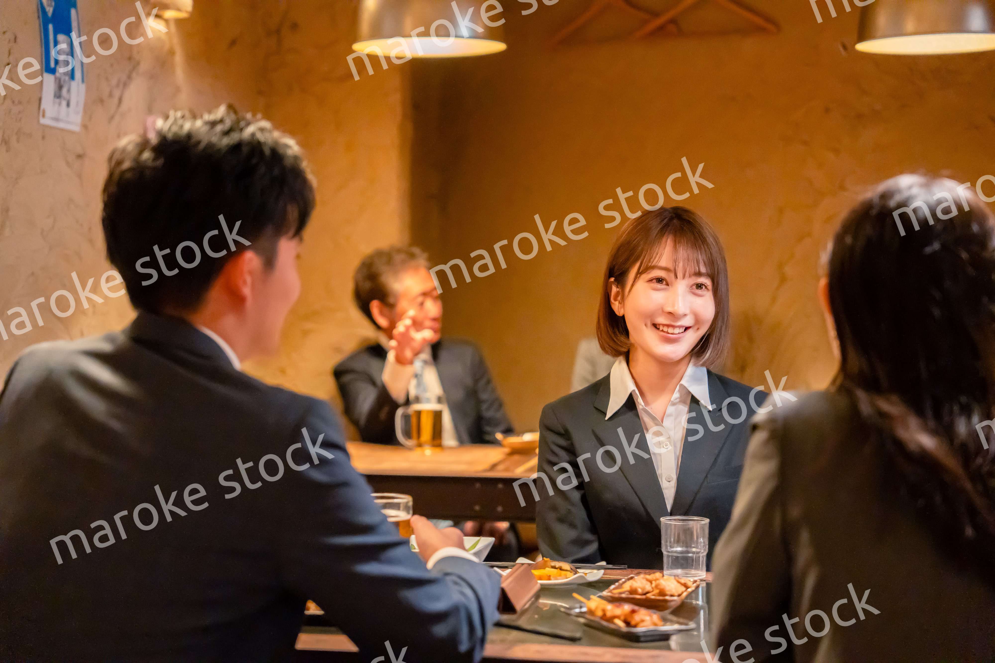 先輩社員と居酒屋で話をするフレッシュな女性