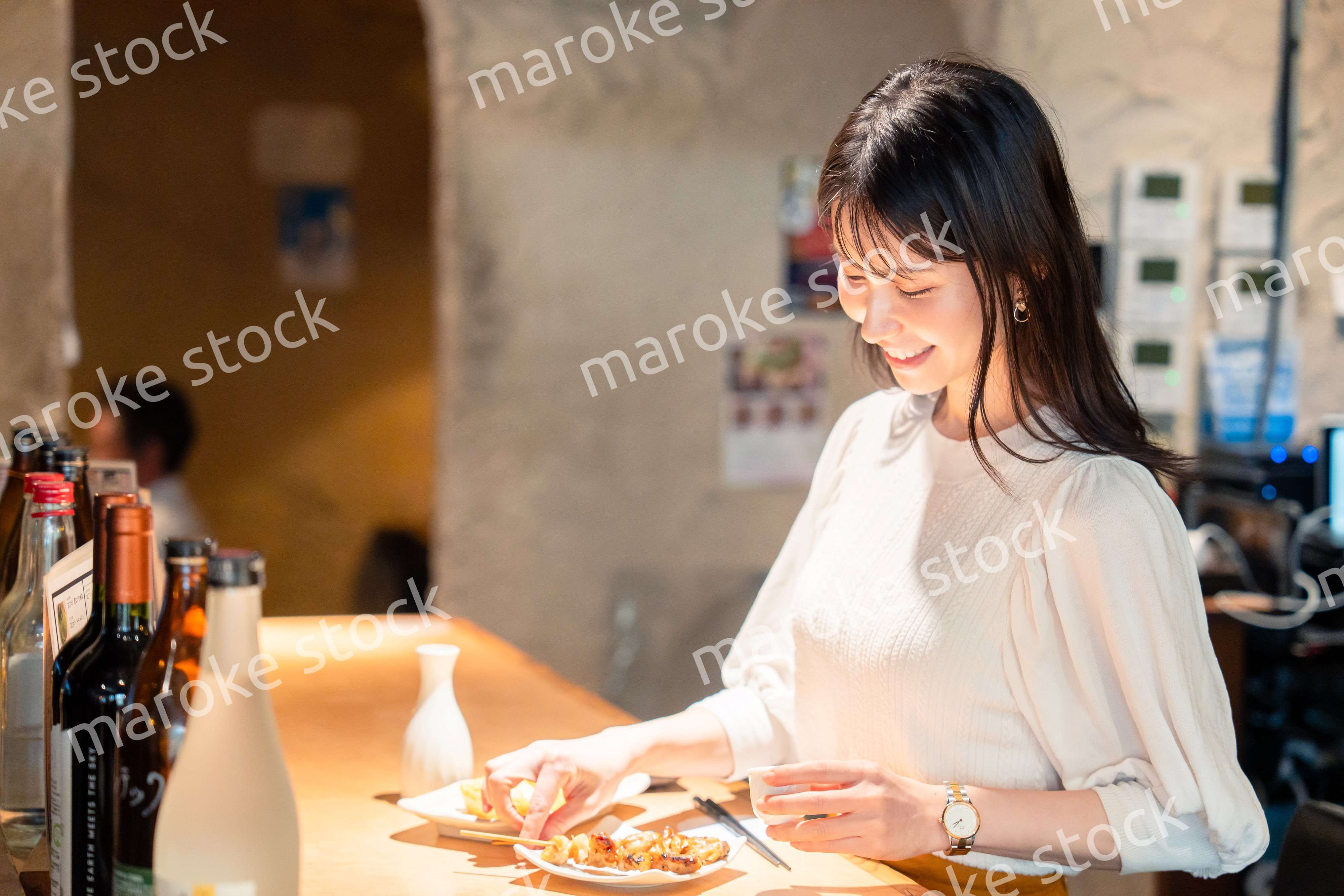 一人でカウンター席に座って焼き鳥を食べる女性