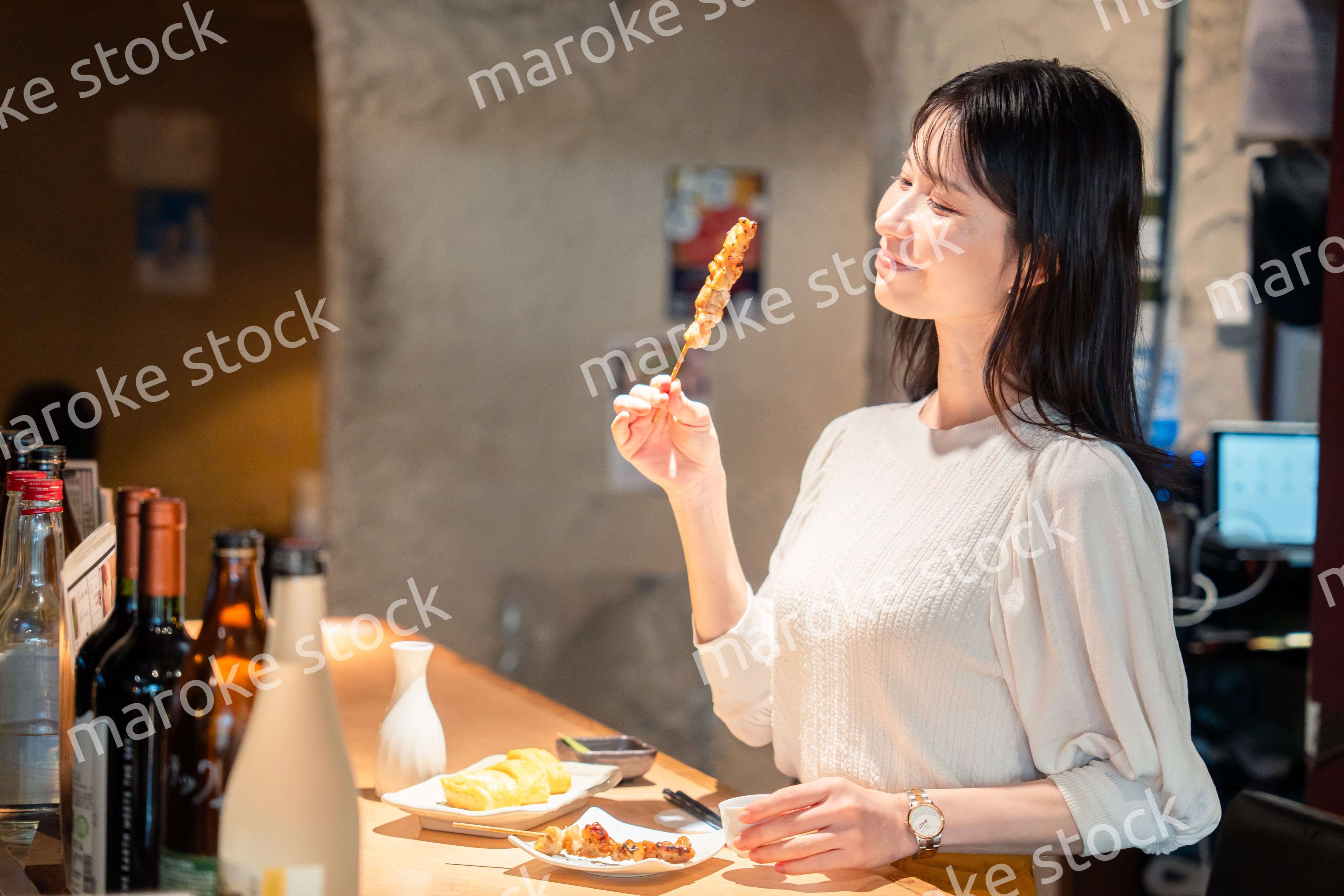一人でカウンター席に座って焼き鳥を食べる女性