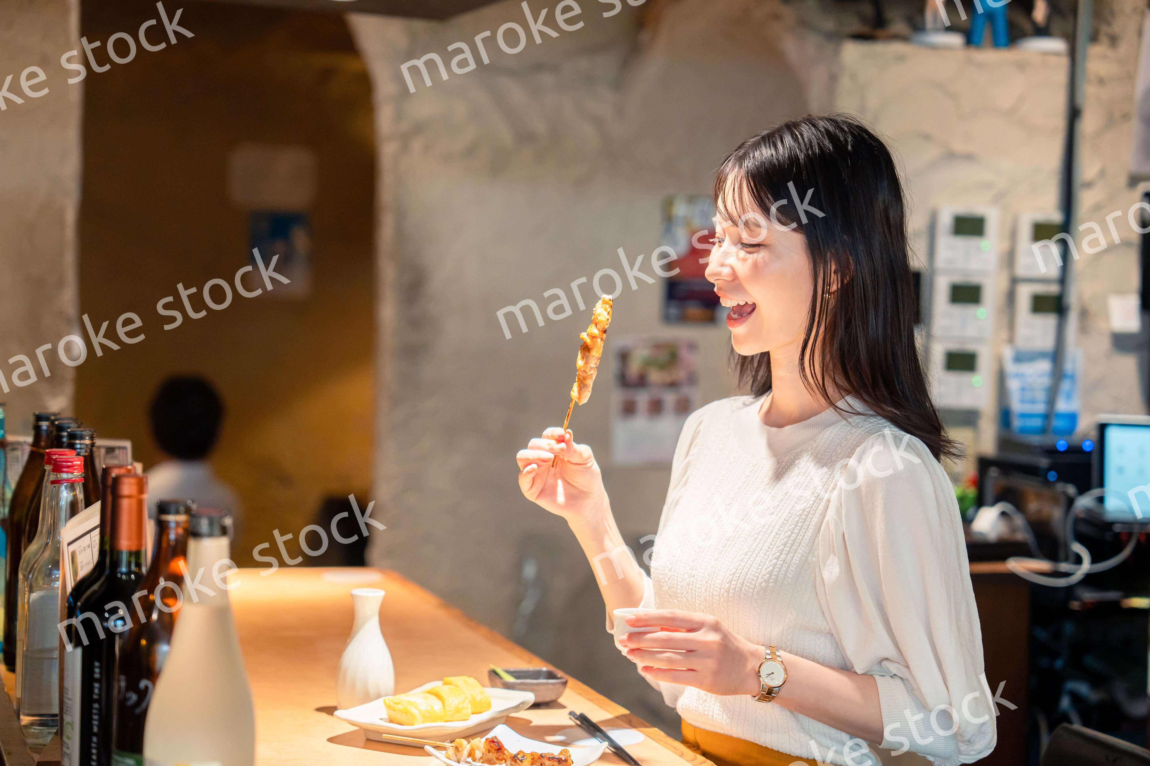 一人でカウンター席に座って焼き鳥を食べる女性