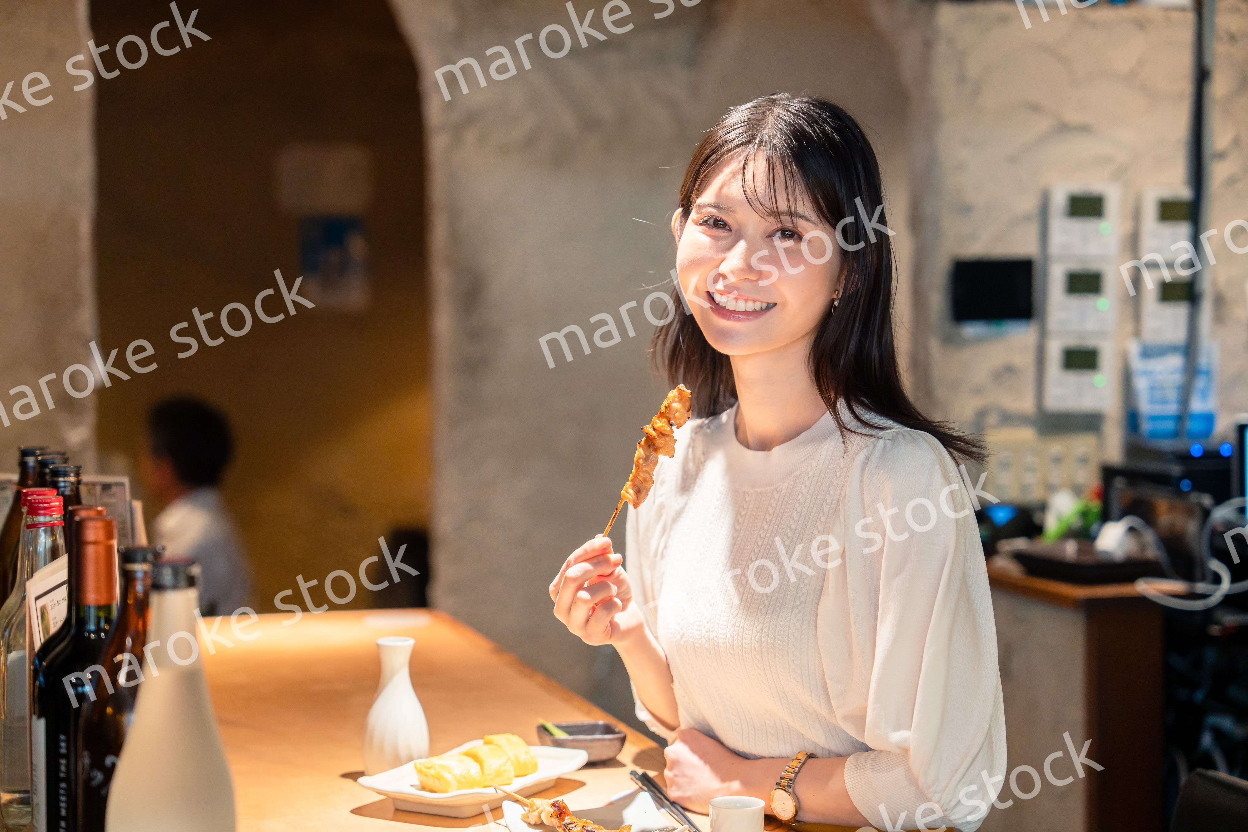 一人でカウンター席に座って焼き鳥を食べる女性