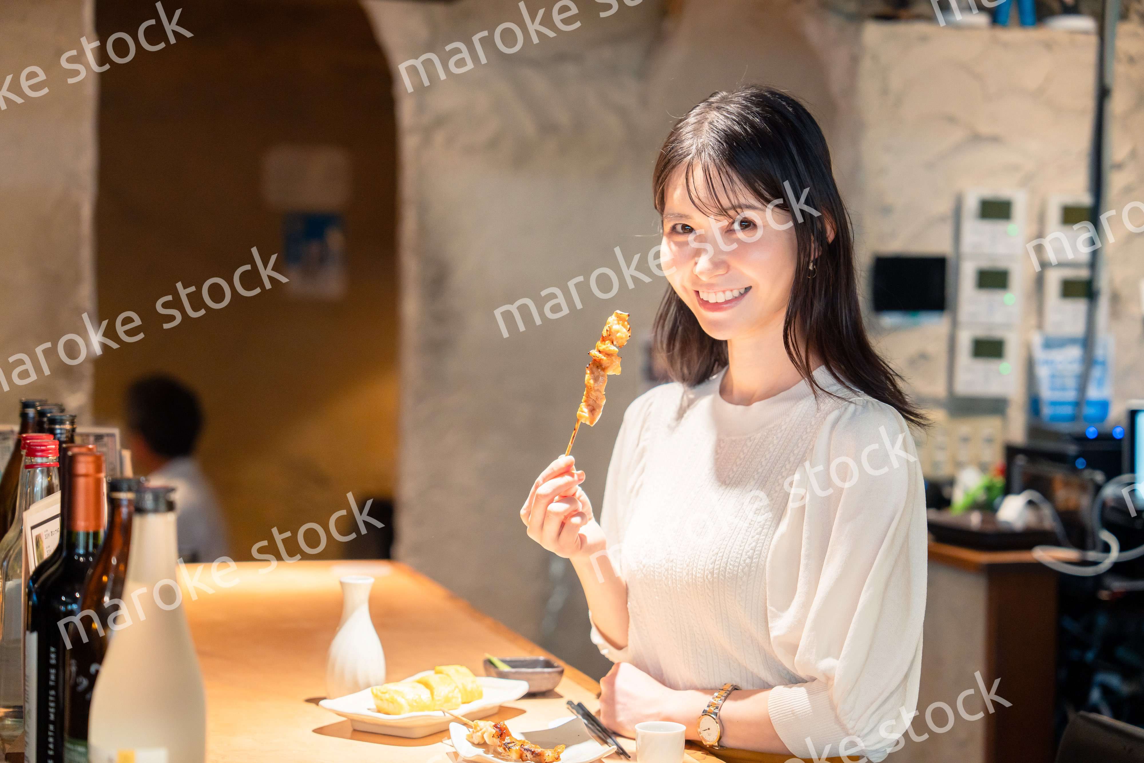 一人でカウンター席に座って焼き鳥を食べる女性