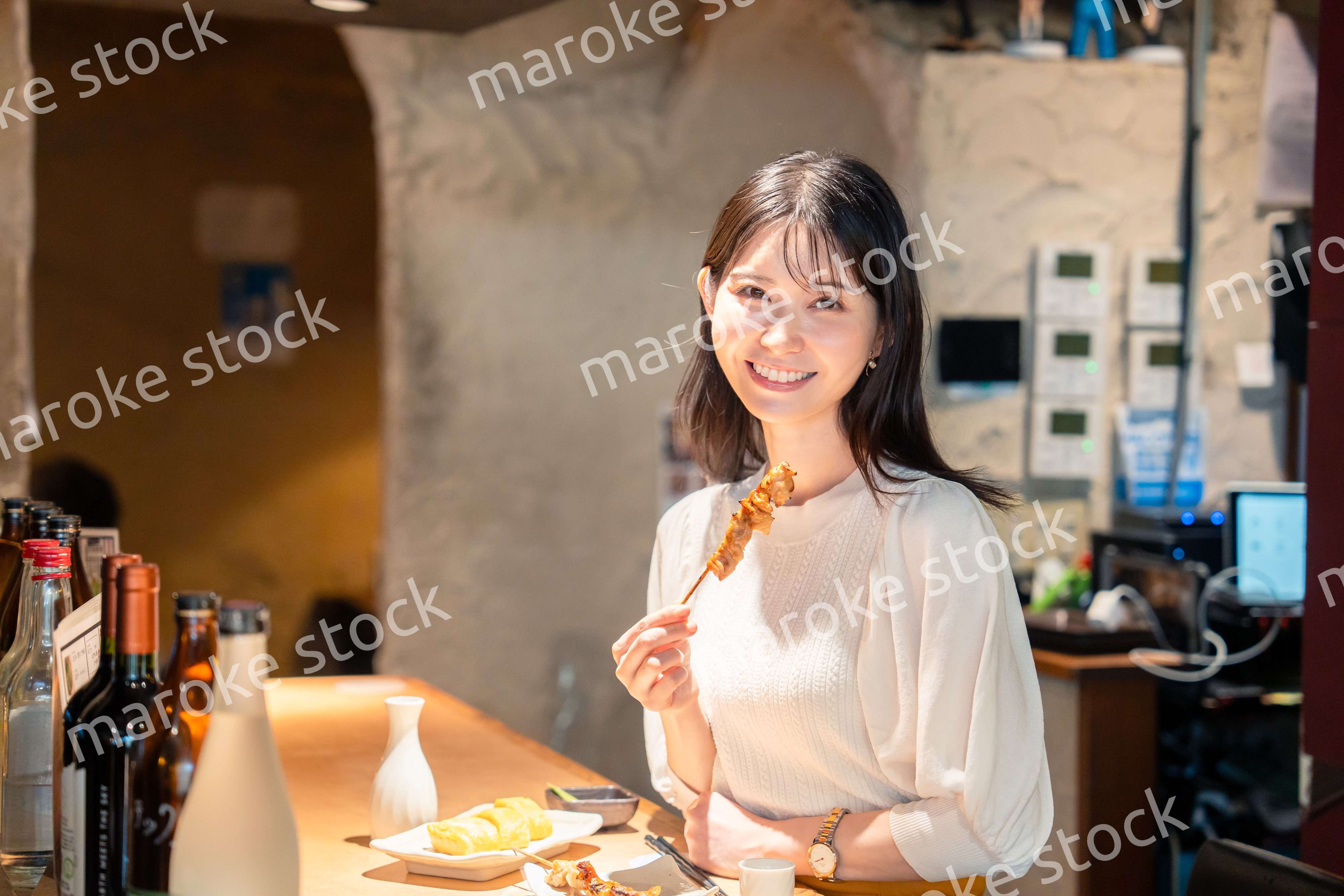 一人でカウンター席に座って焼き鳥を食べる女性