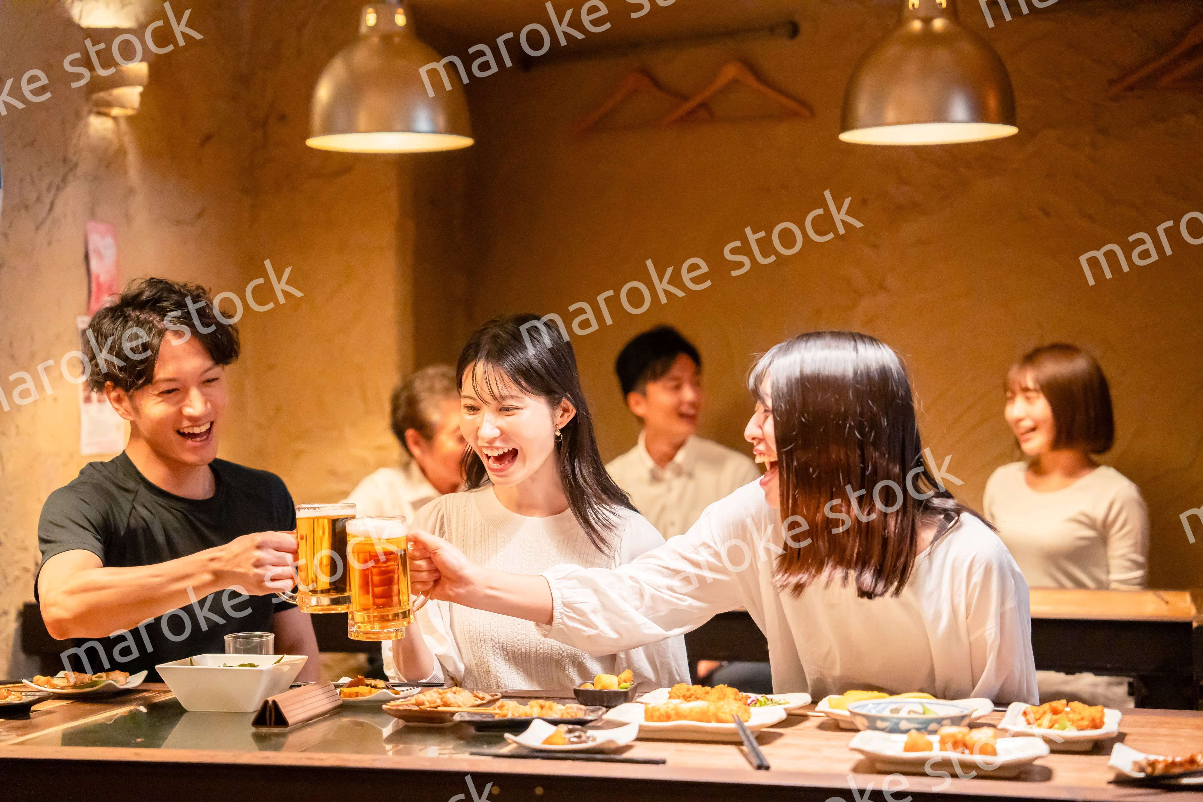 居酒屋でお酒を飲む若い男女