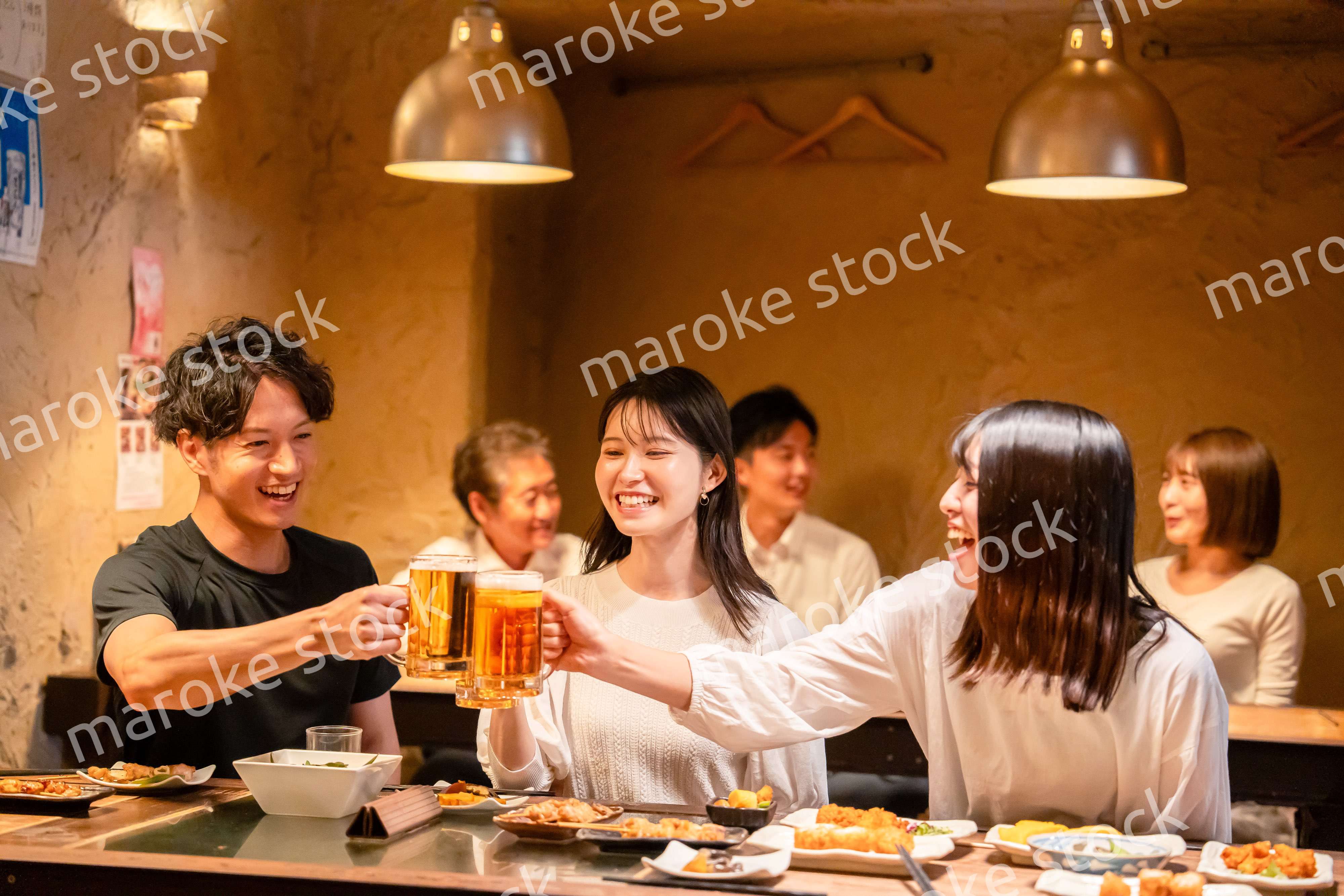 居酒屋でお酒を飲む若い男女