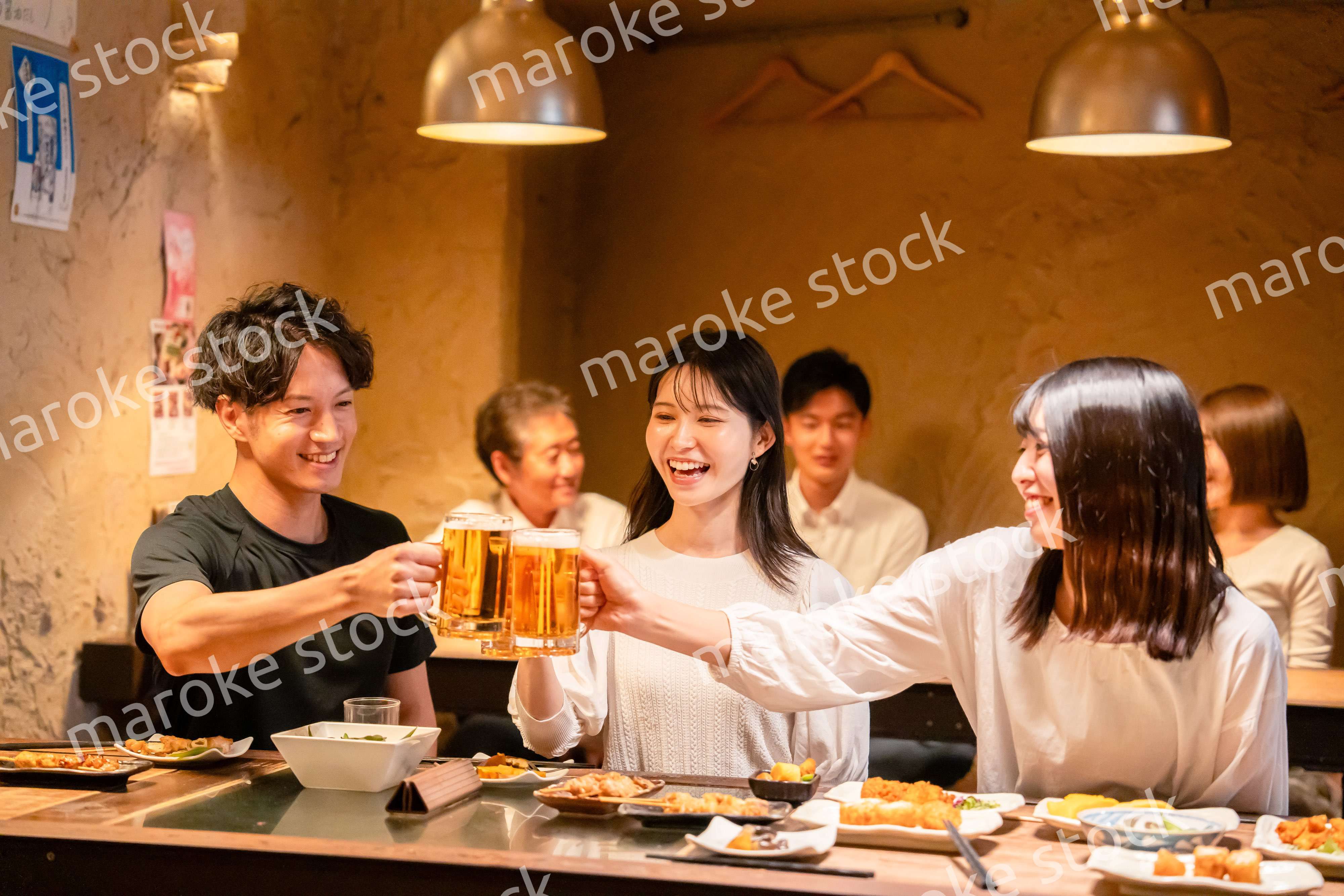 居酒屋でお酒を飲む若い男女