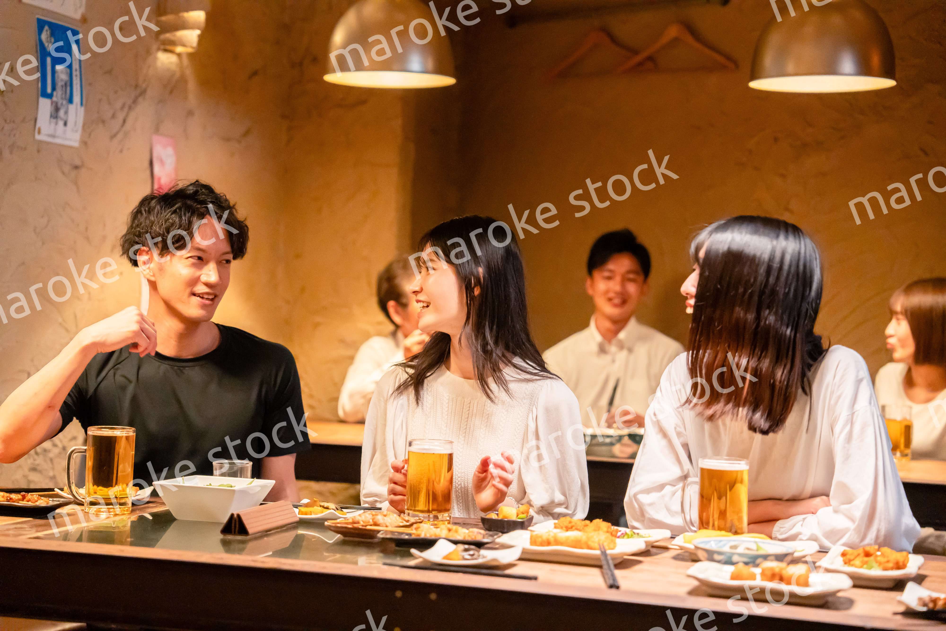 居酒屋でお酒を飲む若い男女