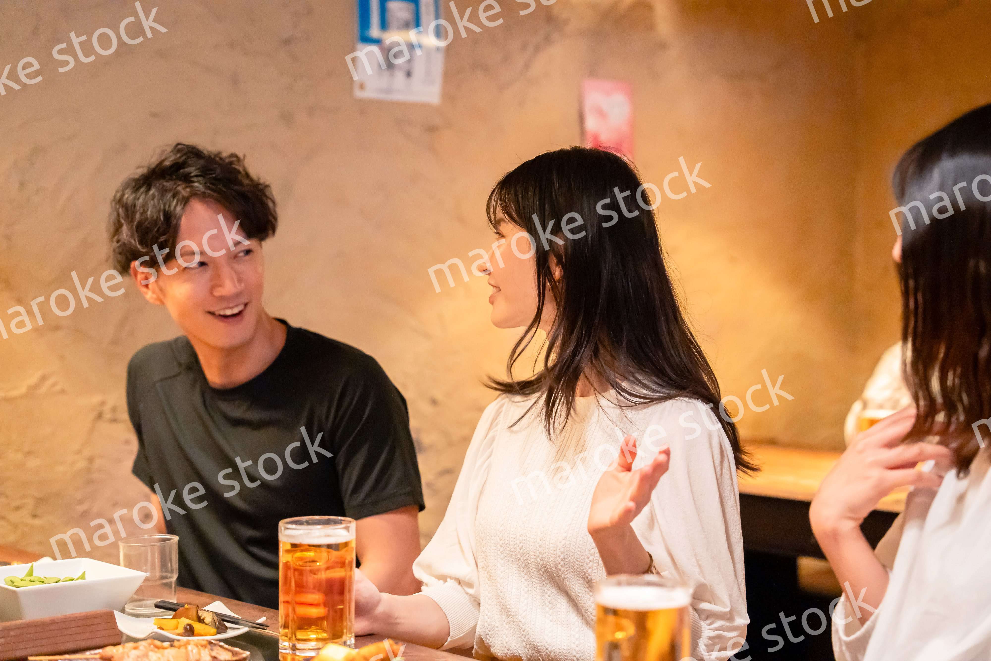 居酒屋でお酒を飲む若い男女