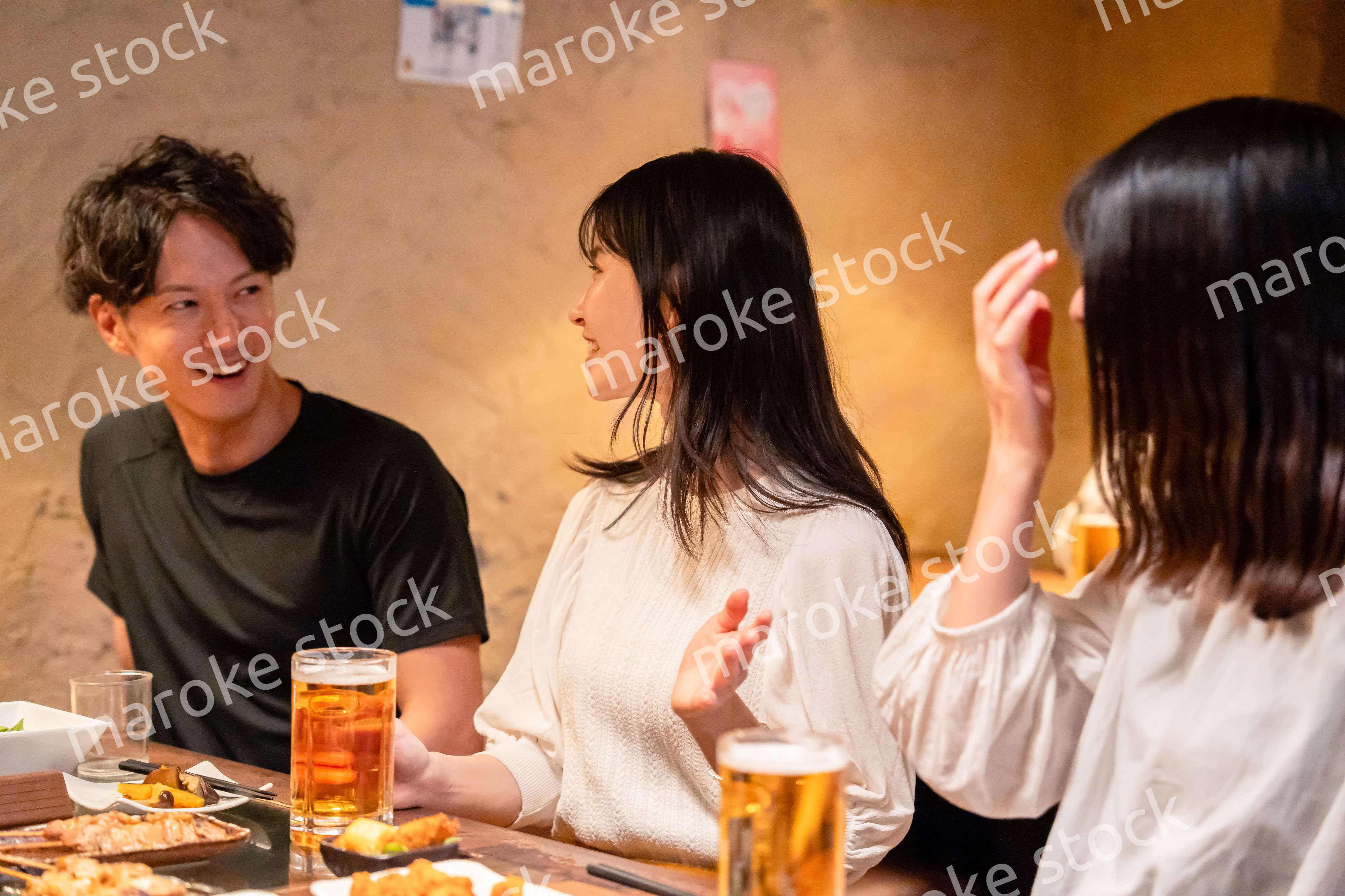 居酒屋でお酒を飲む若い男女