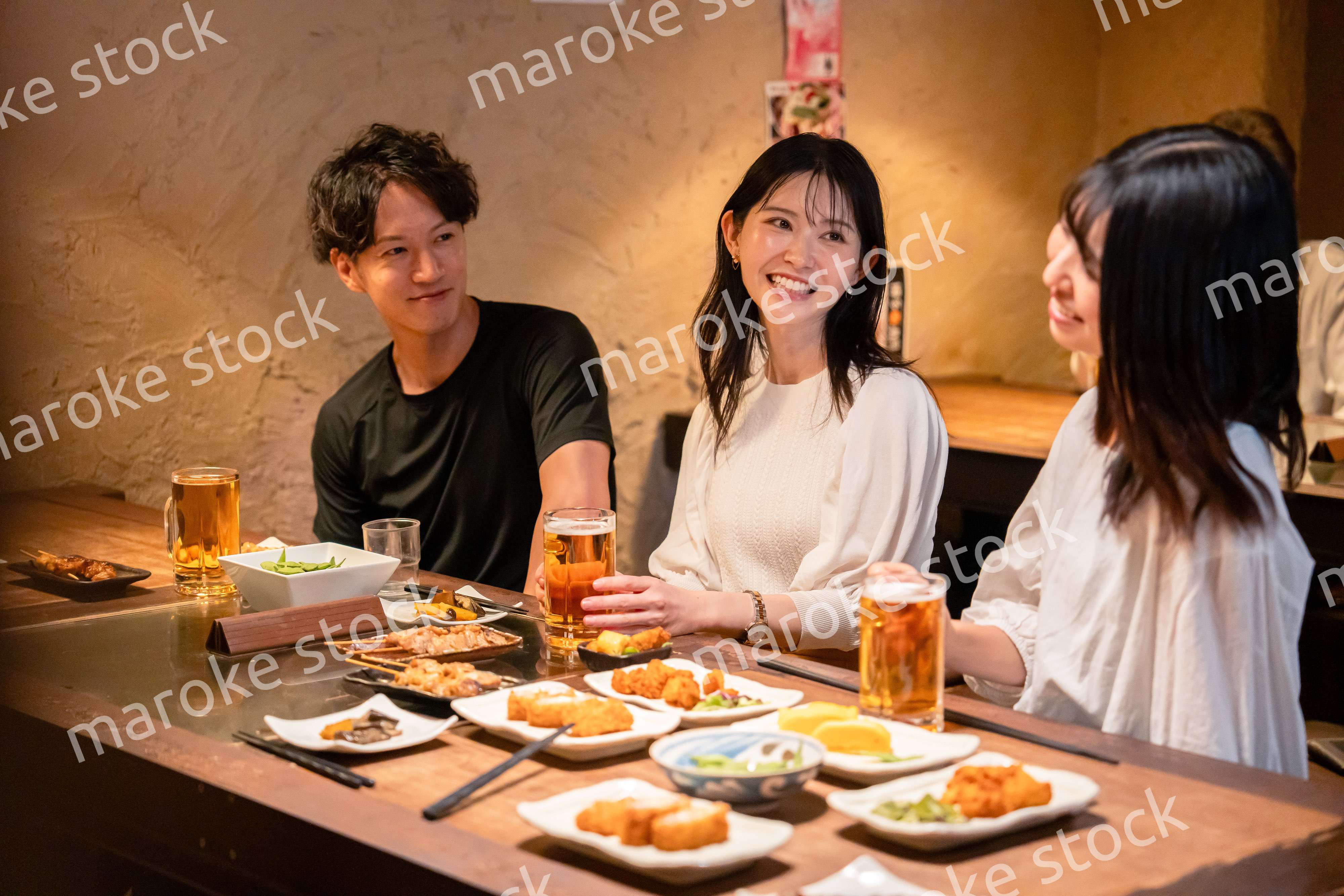 居酒屋でお酒を飲む若い男女