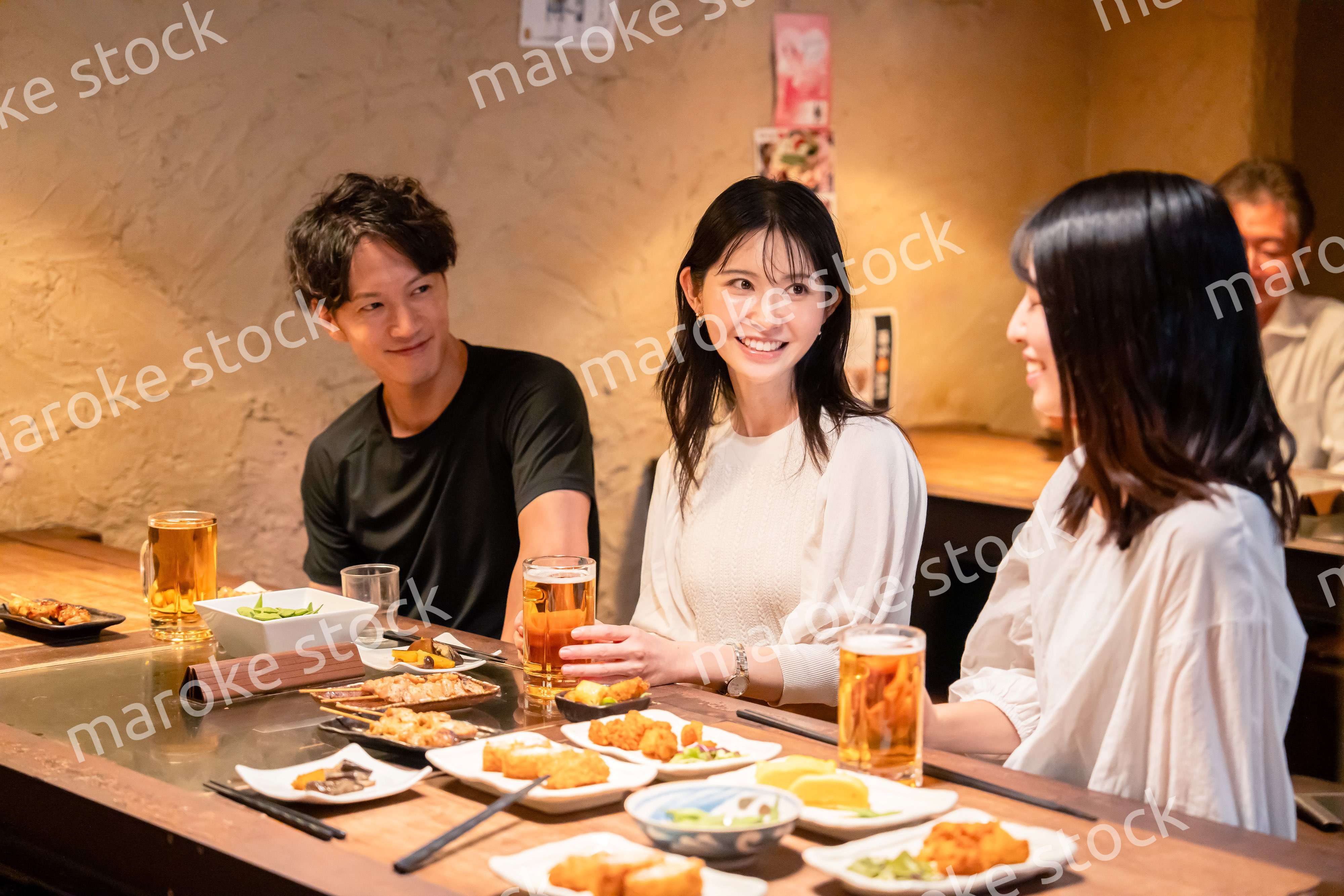 居酒屋でお酒を飲む若い男女