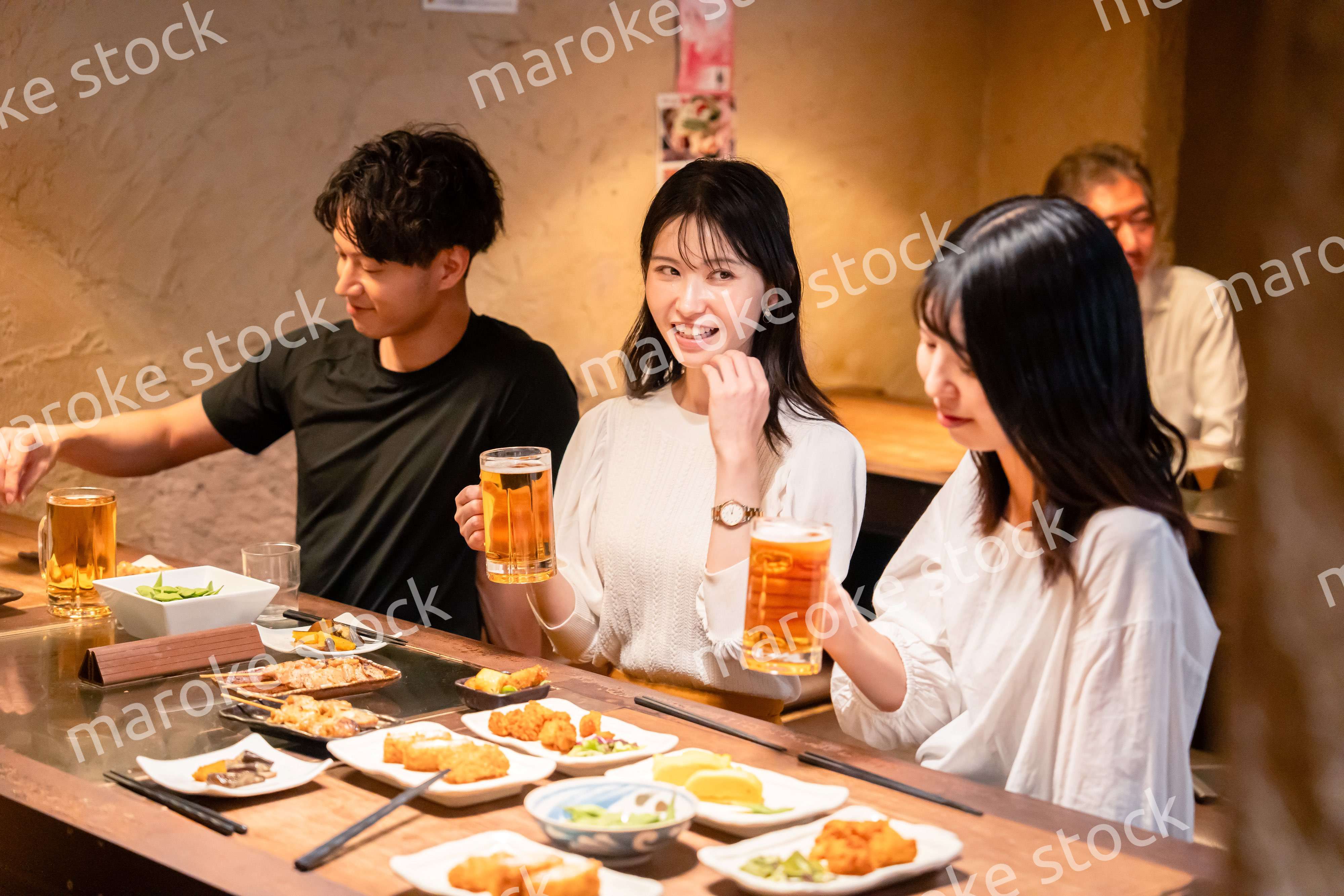 居酒屋でお酒を飲む若い男女