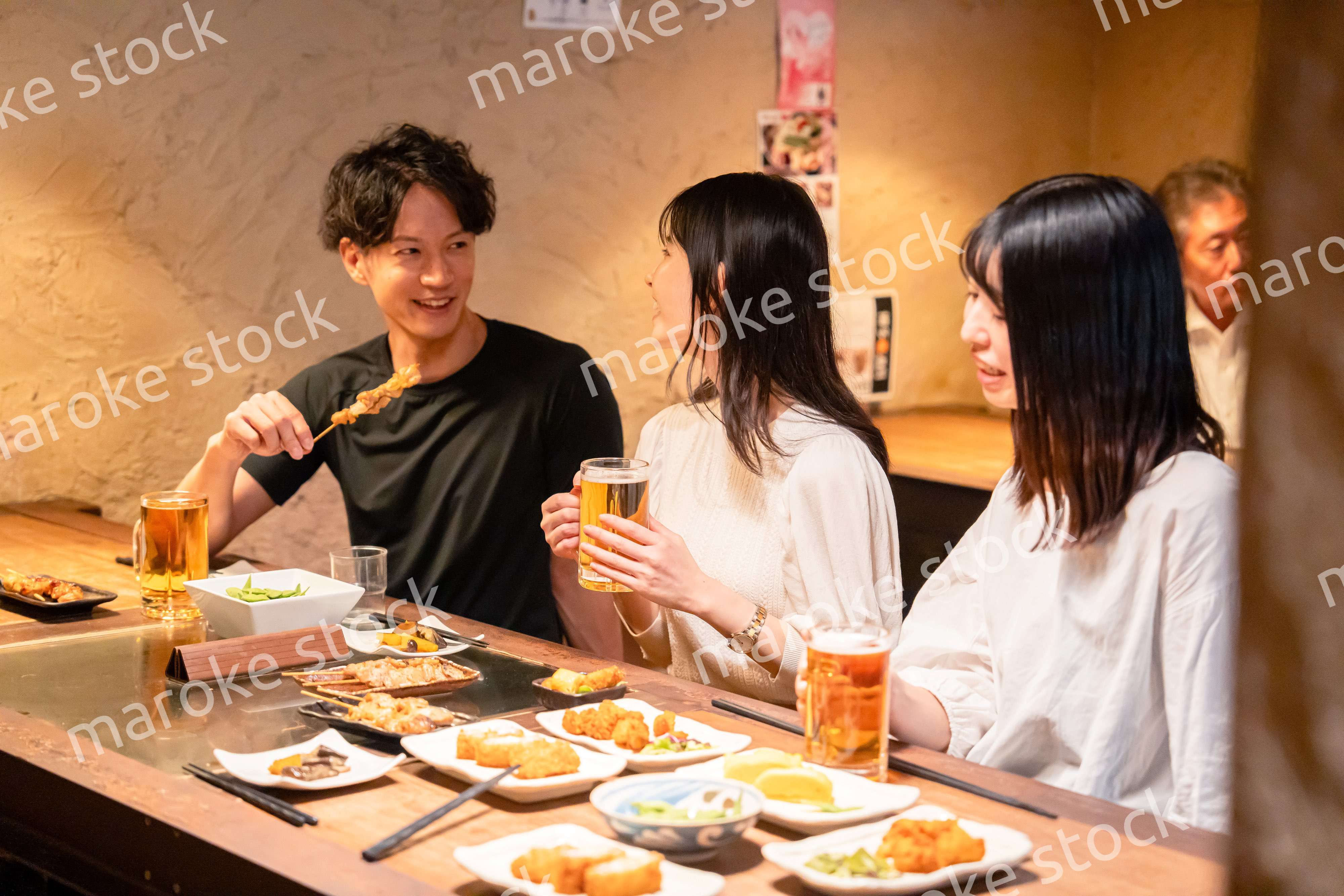 居酒屋でお酒を飲む若い男女