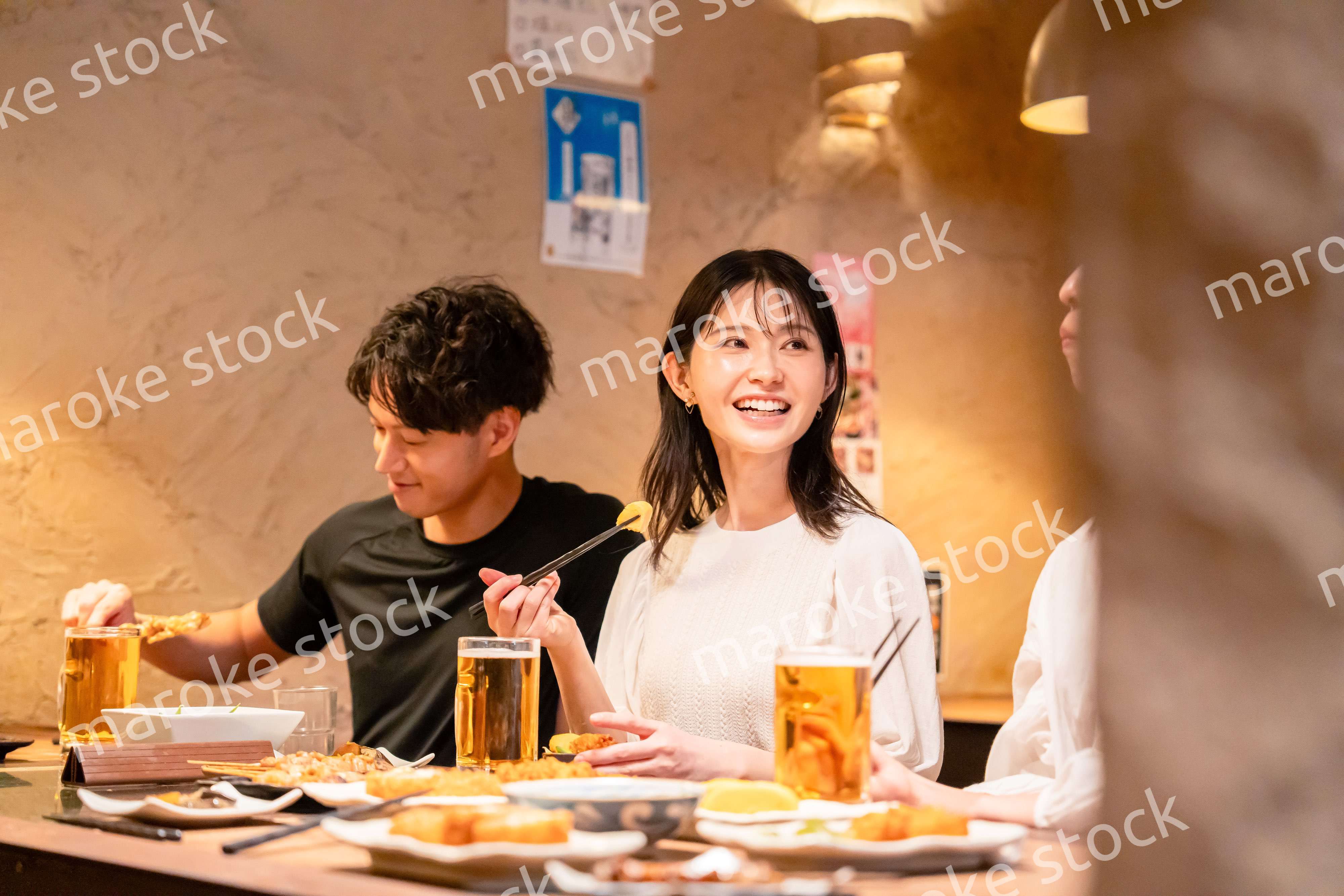 居酒屋でお酒を飲む若い男女