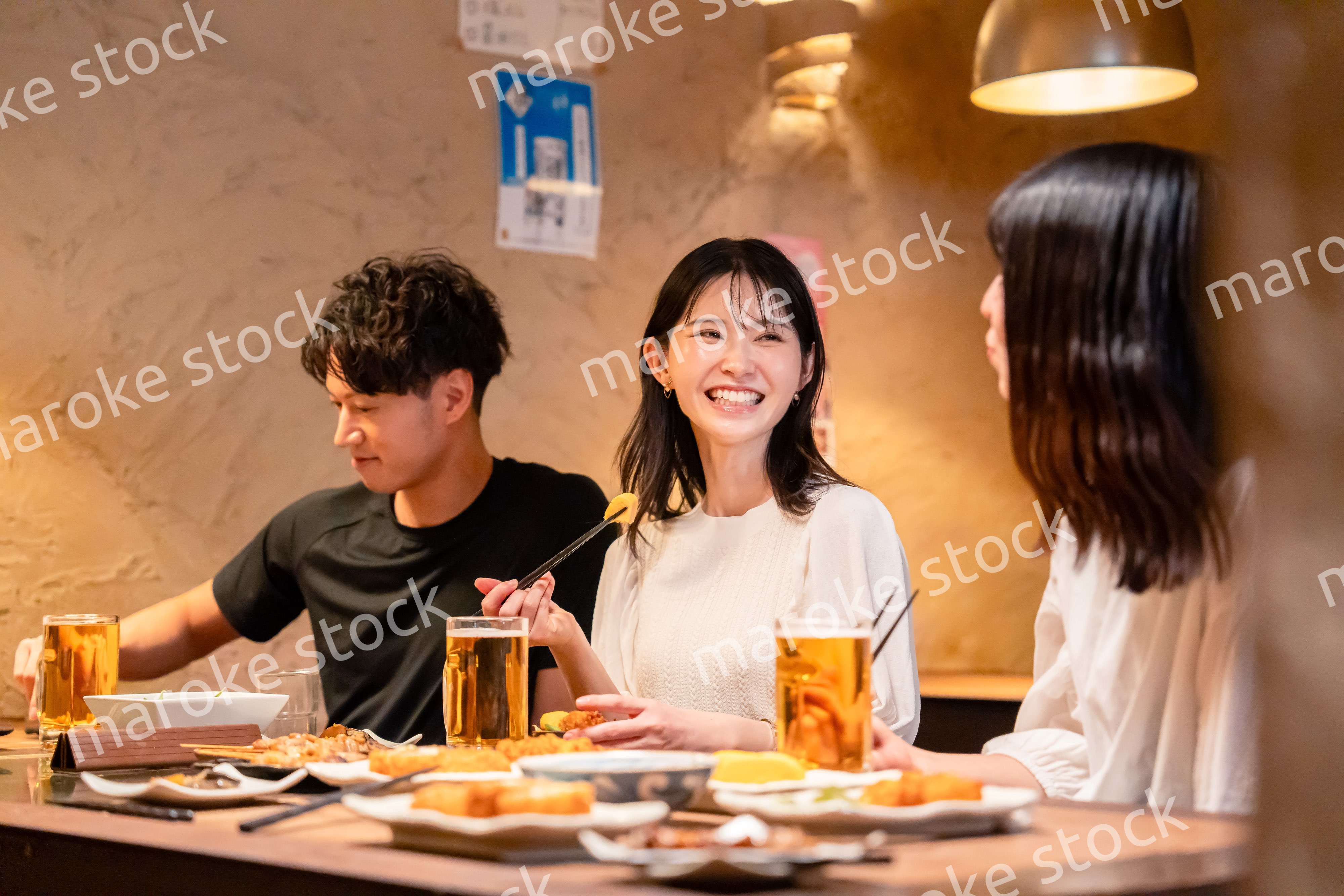 居酒屋でお酒を飲む若い男女