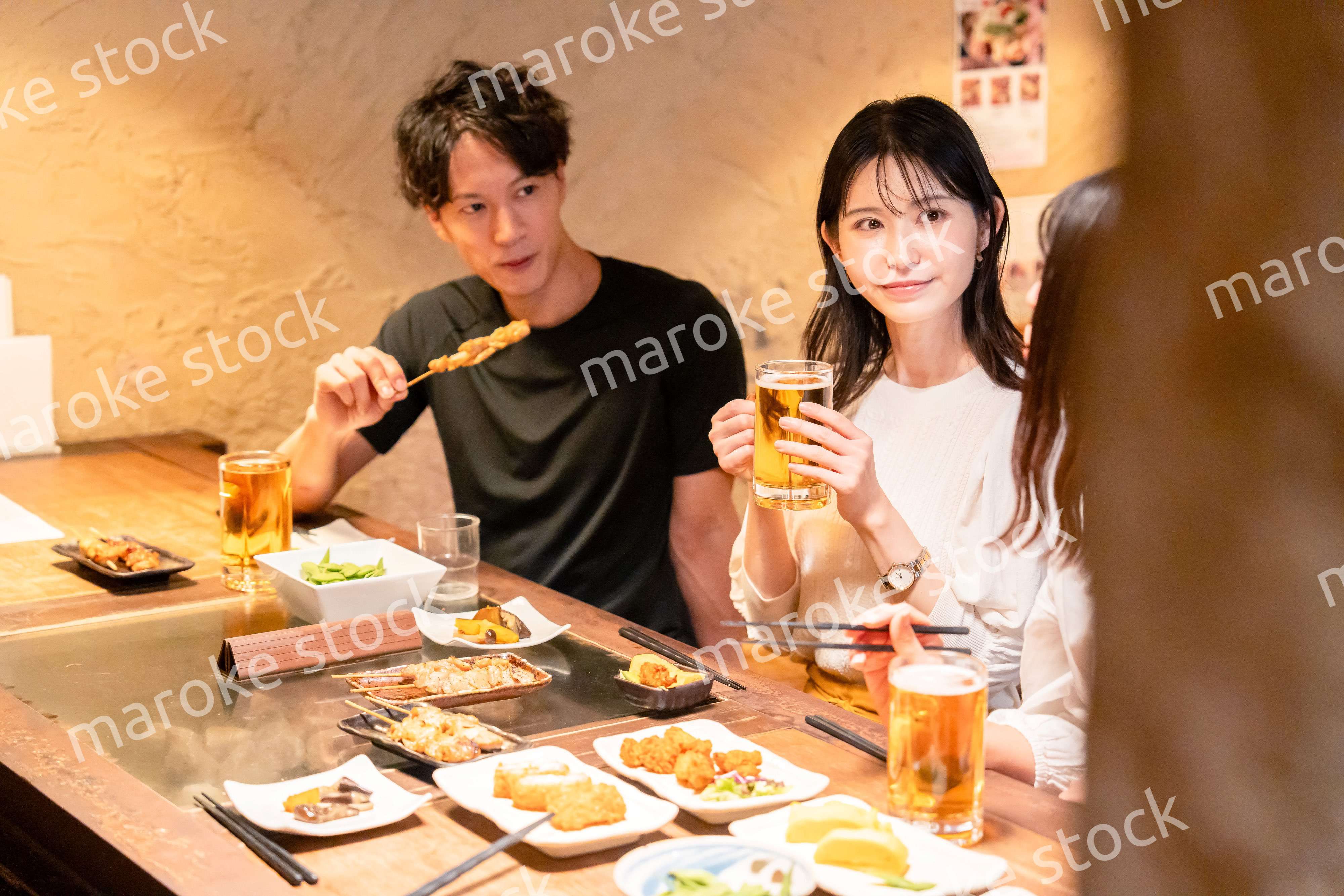 居酒屋でお酒を飲む若い男女