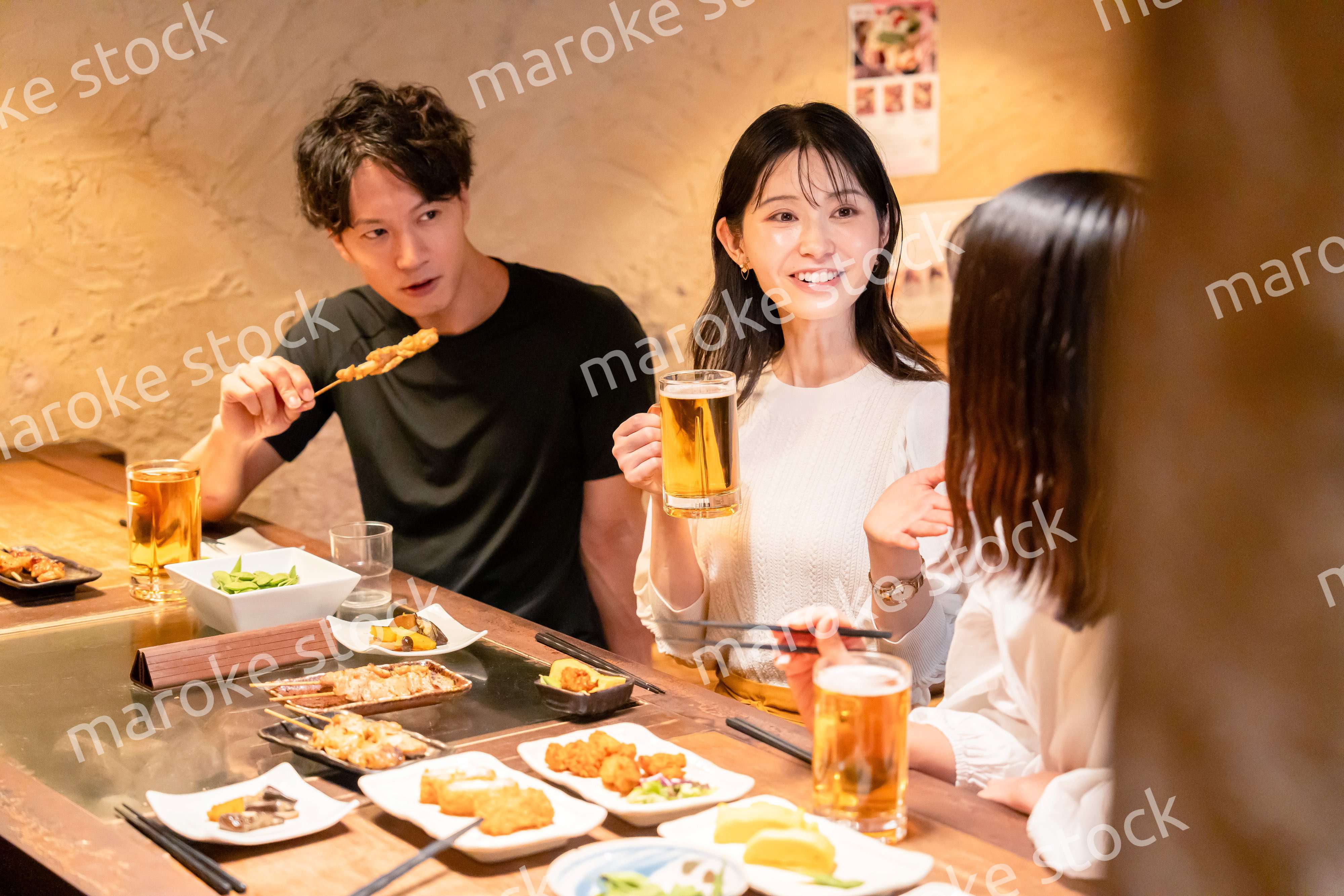 居酒屋でお酒を飲む若い男女