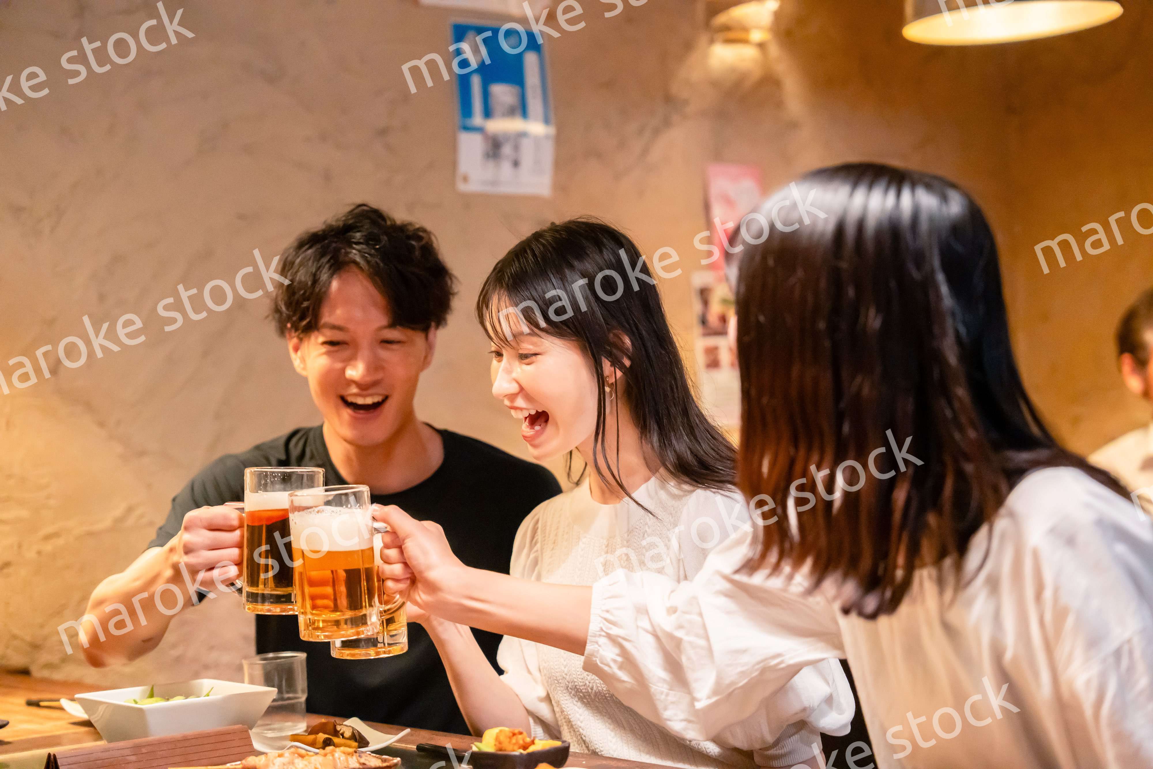 居酒屋でお酒を飲む若い男女