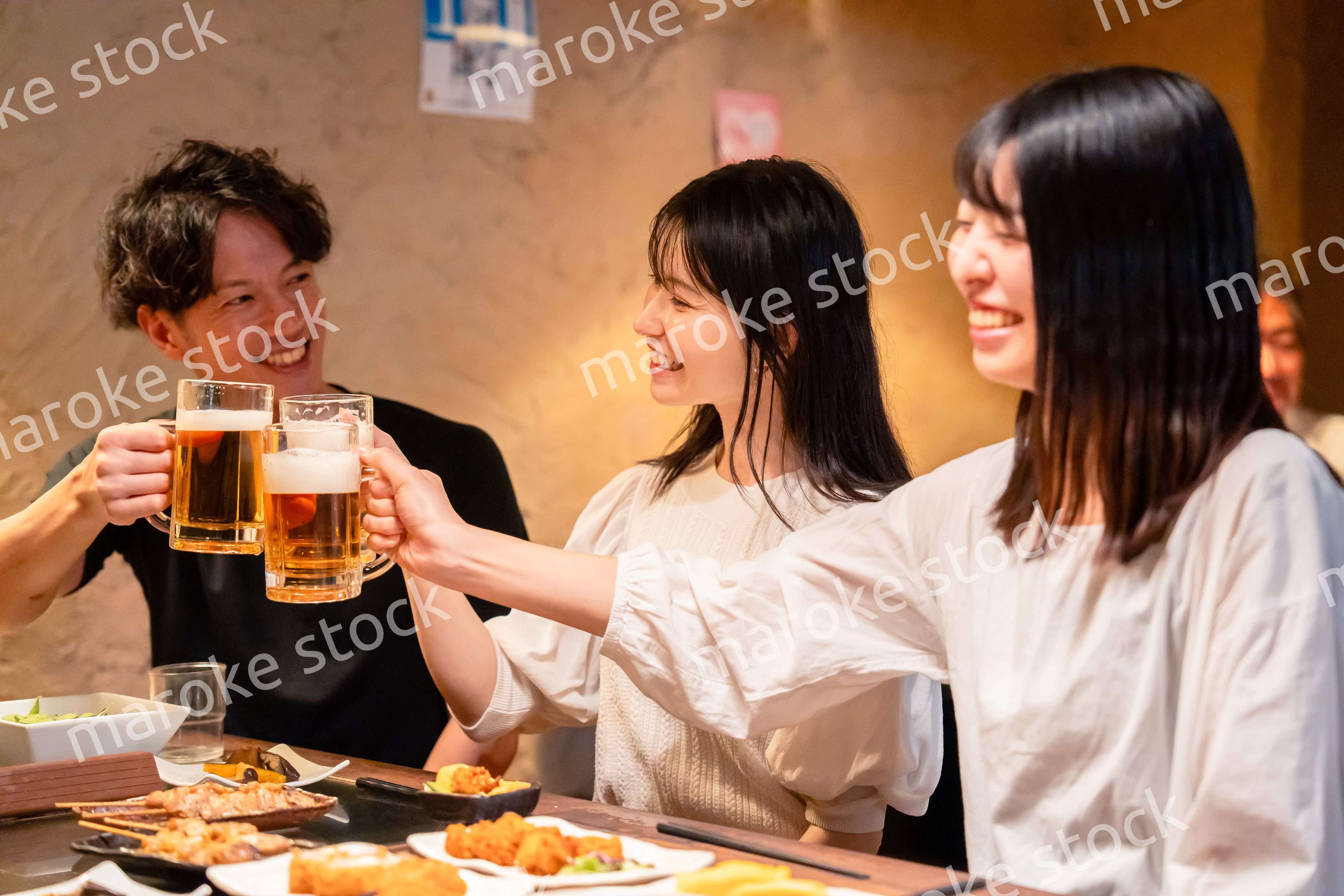居酒屋でお酒を飲む若い男女