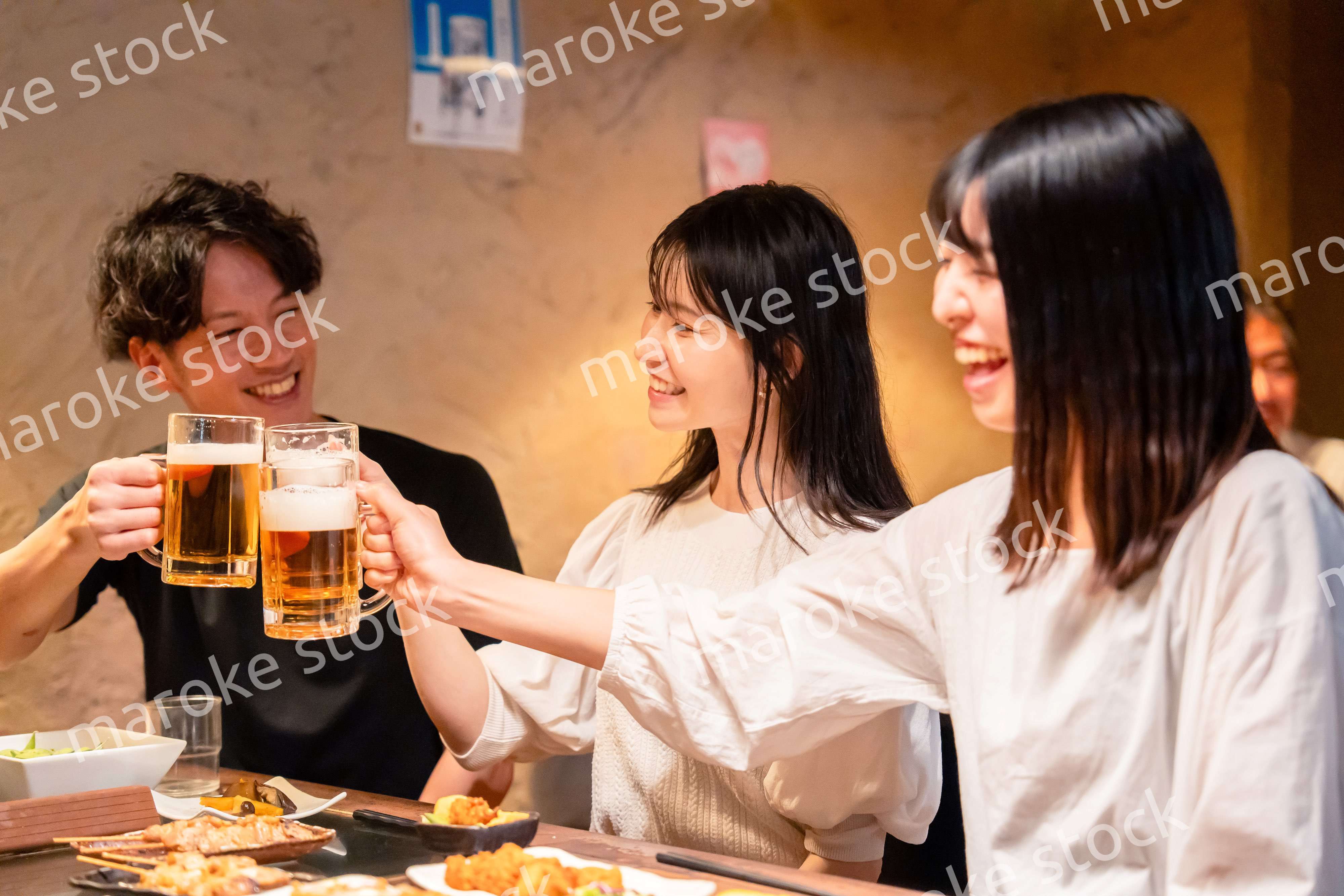 居酒屋でお酒を飲む若い男女