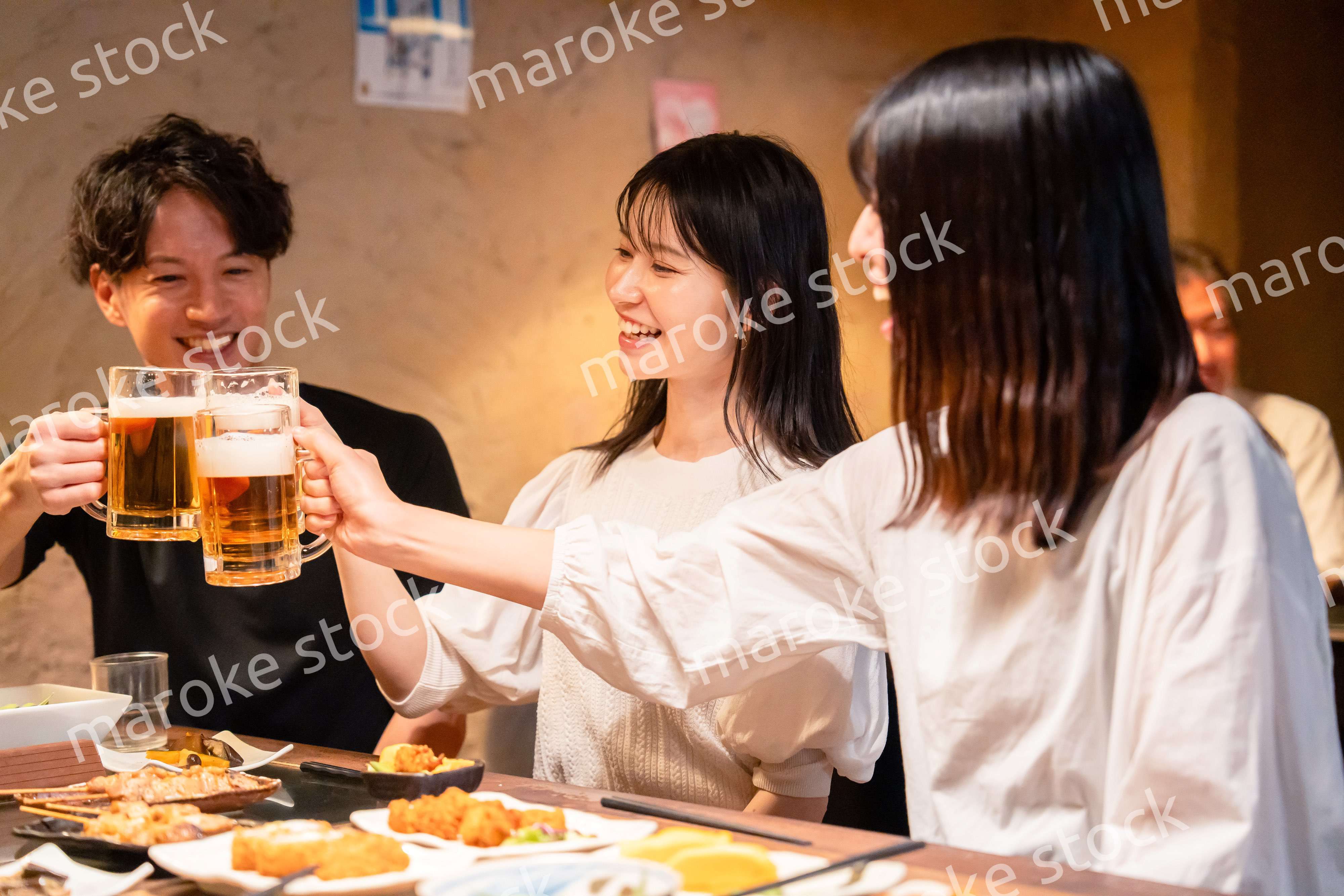 居酒屋でお酒を飲む若い男女