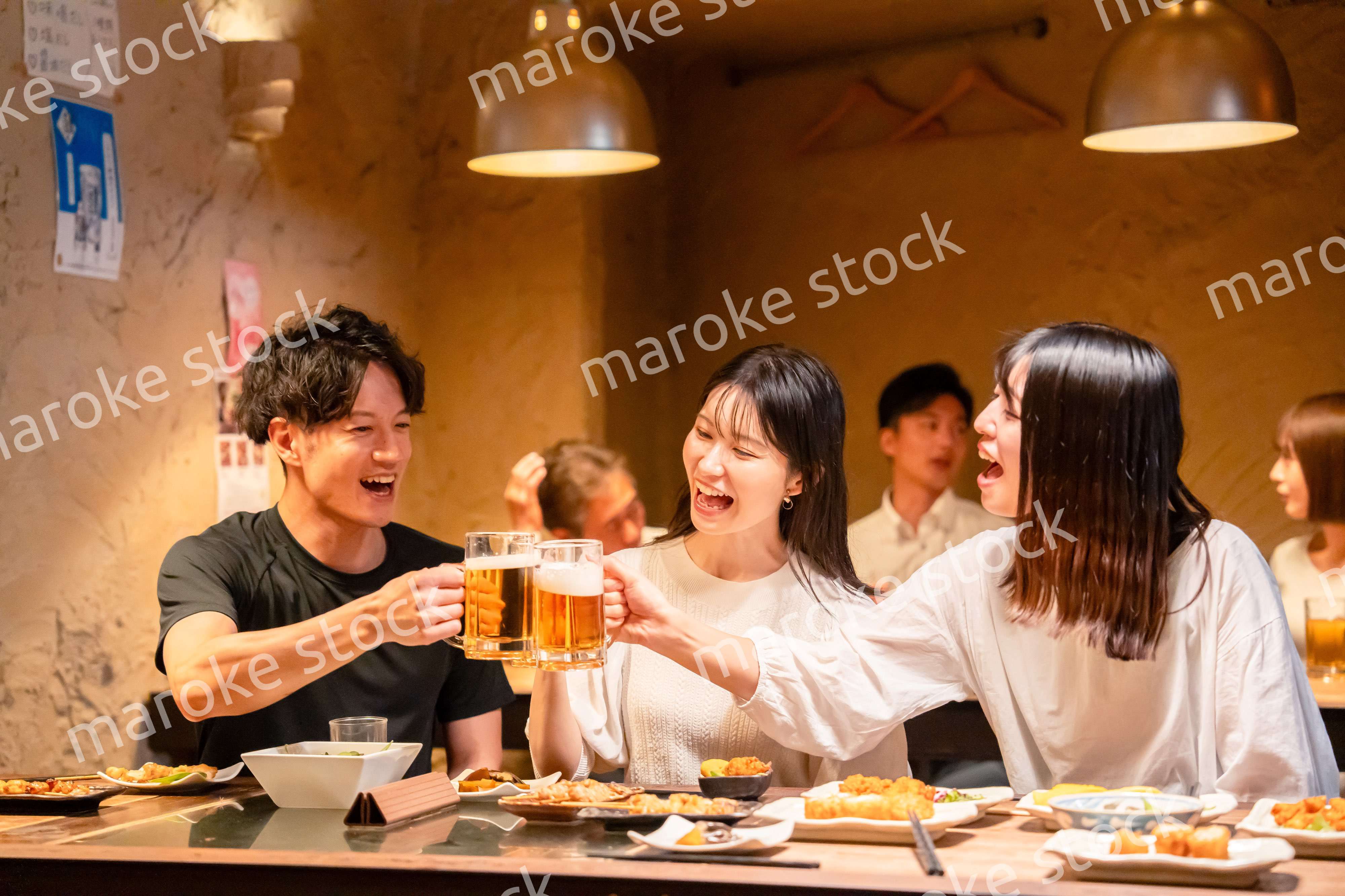 居酒屋でお酒を飲む若い男女