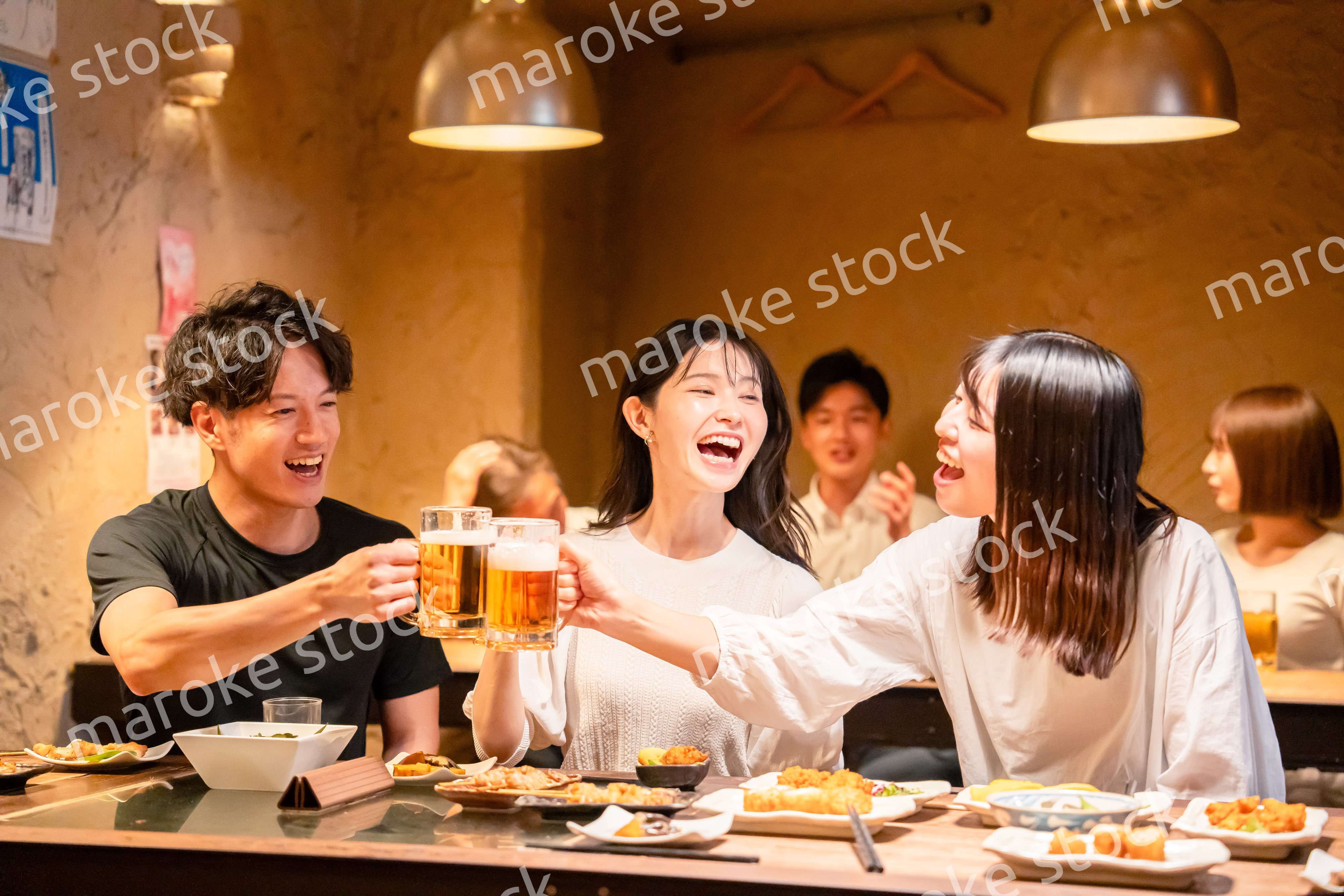 居酒屋でお酒を飲む若い男女