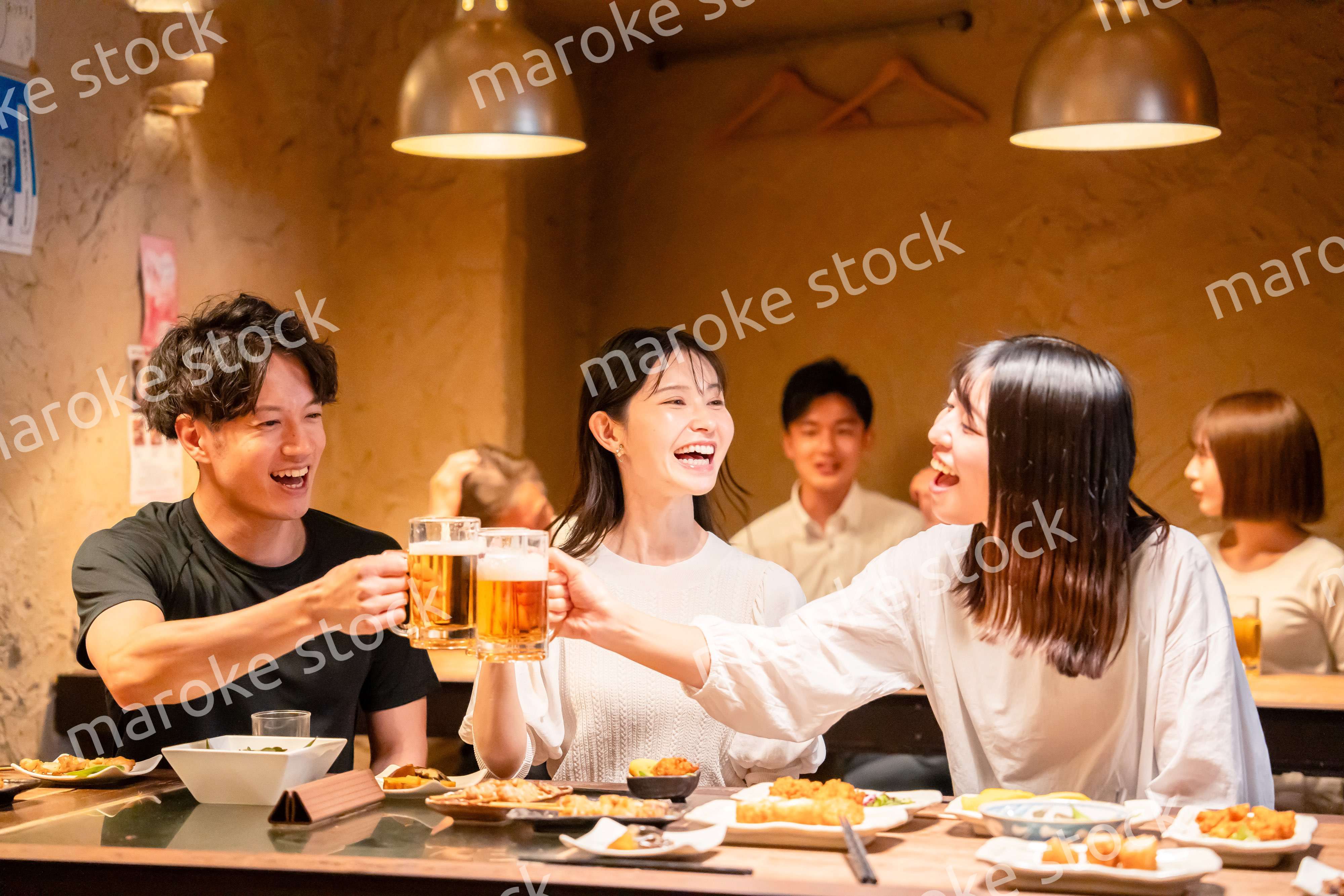 居酒屋でお酒を飲む若い男女