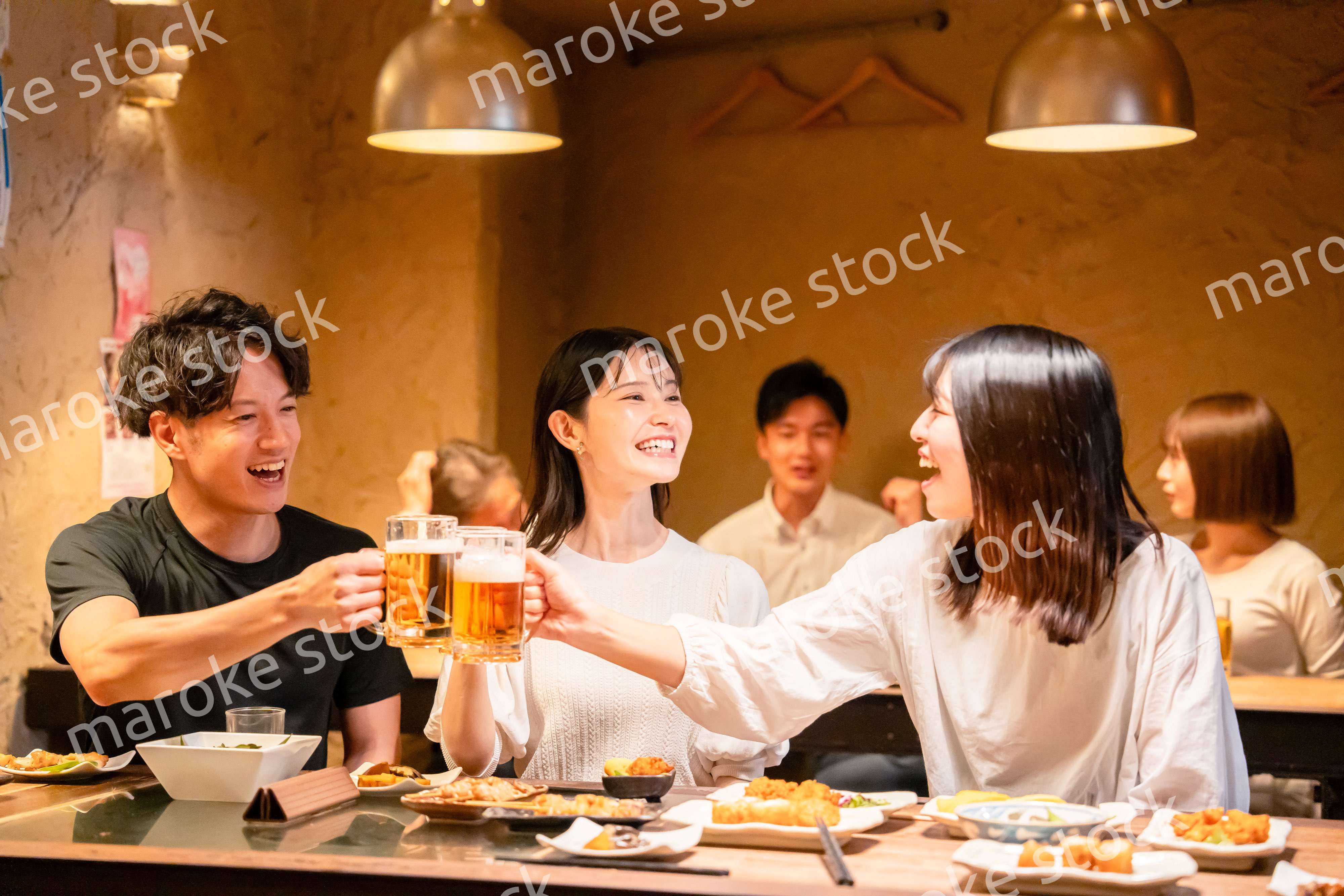 居酒屋でお酒を飲む若い男女