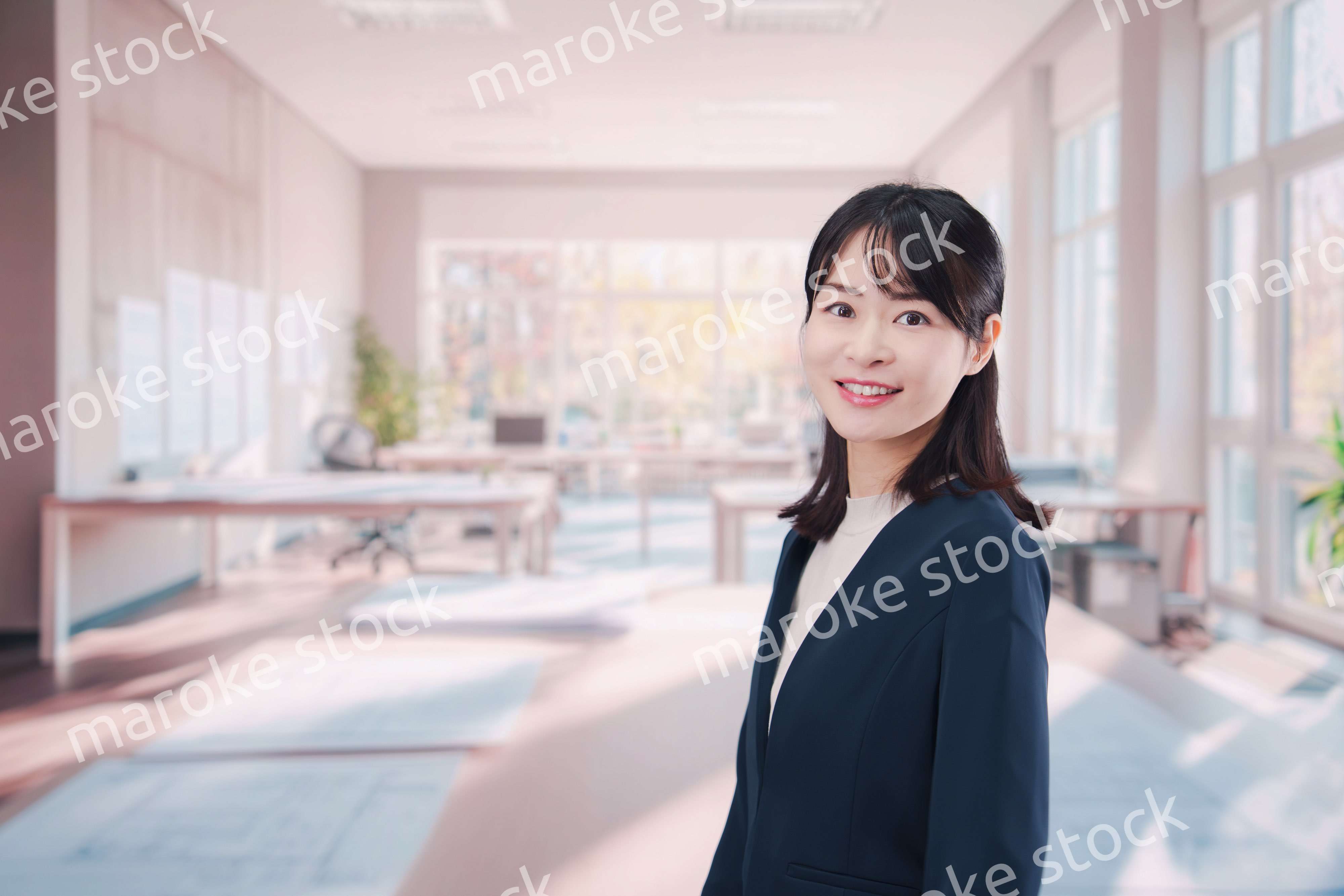 オフィスカジュアルでオフィスに立つ若い女性