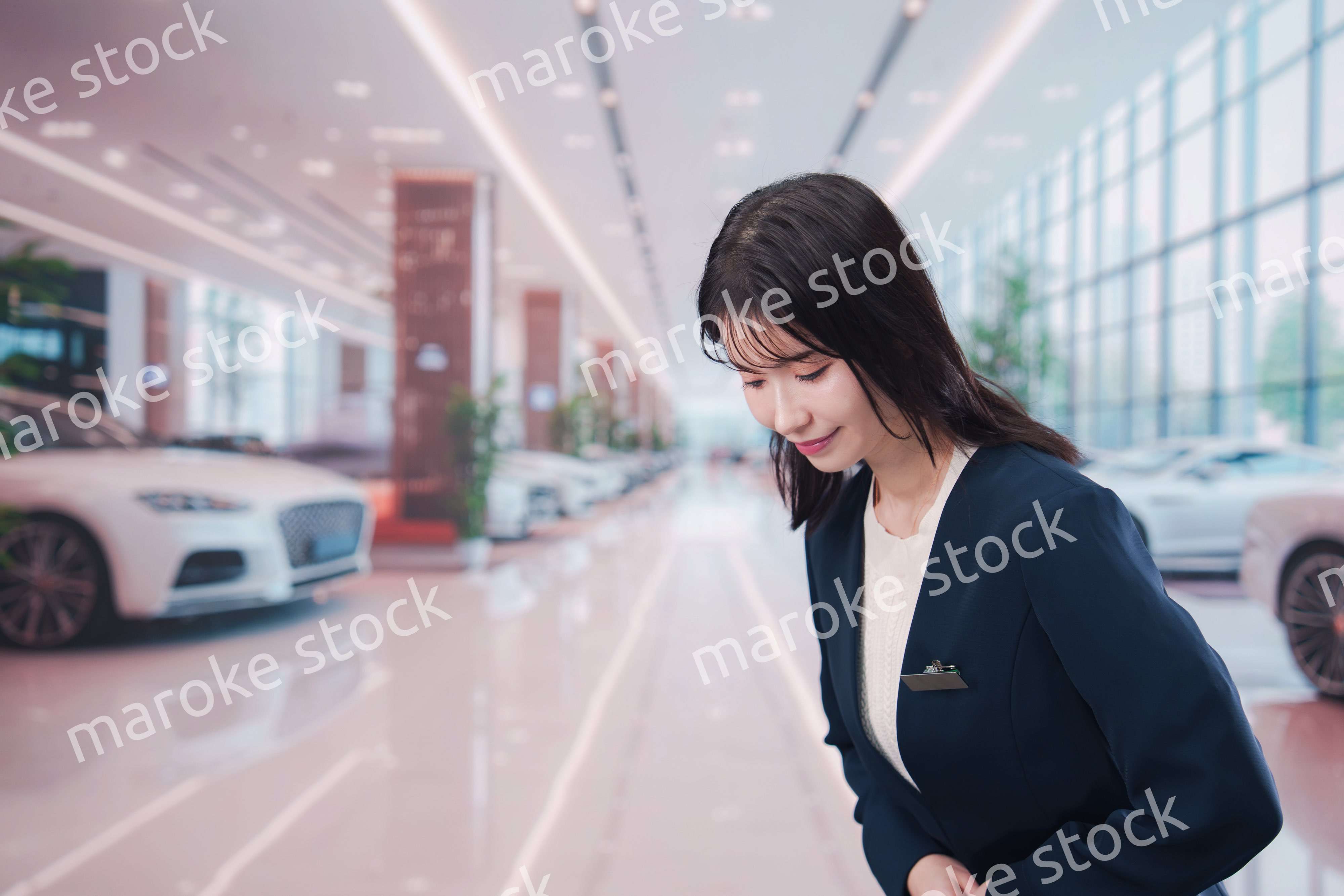 カーディーラーで接客をする若い女性