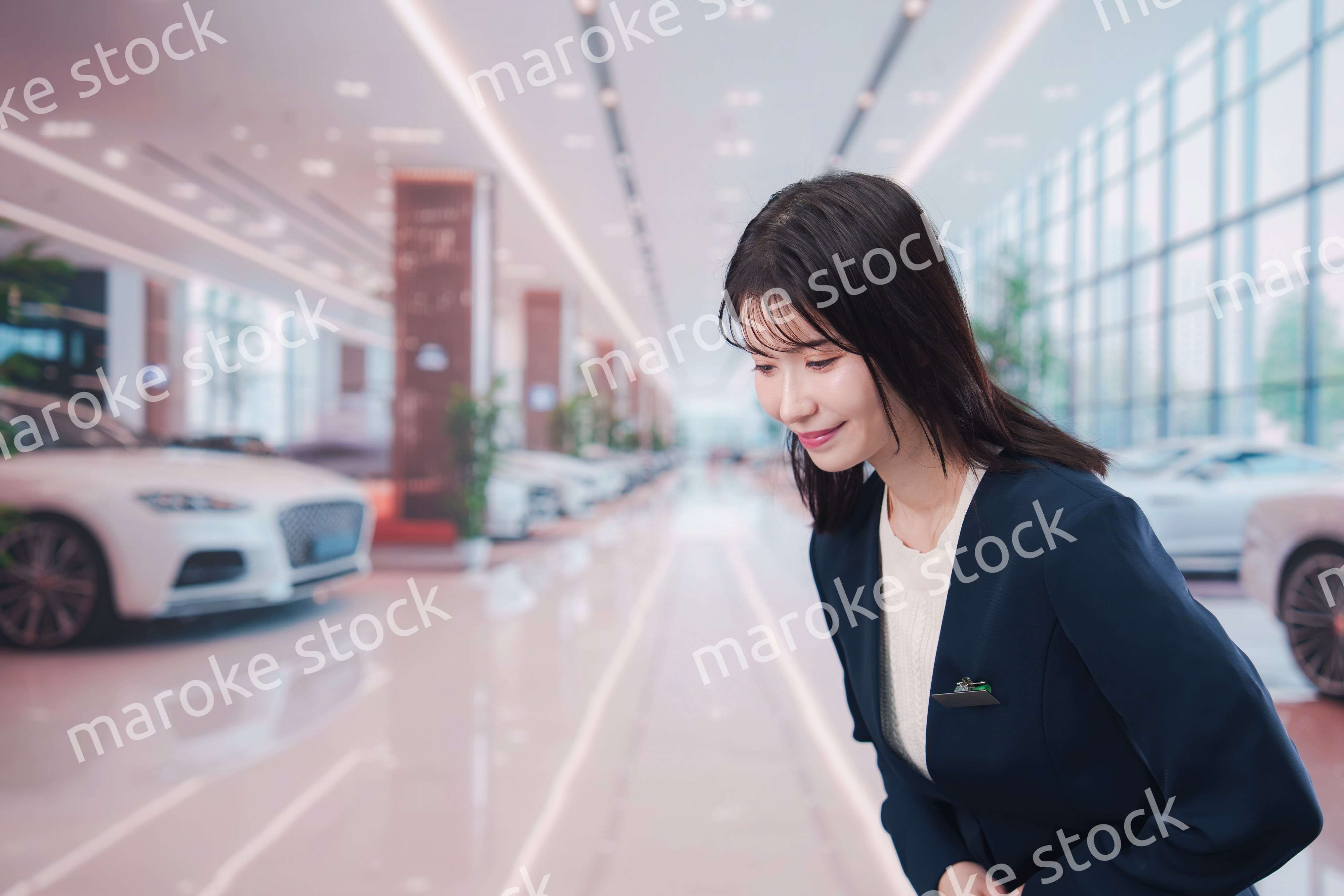 カーディーラーで接客をする若い女性