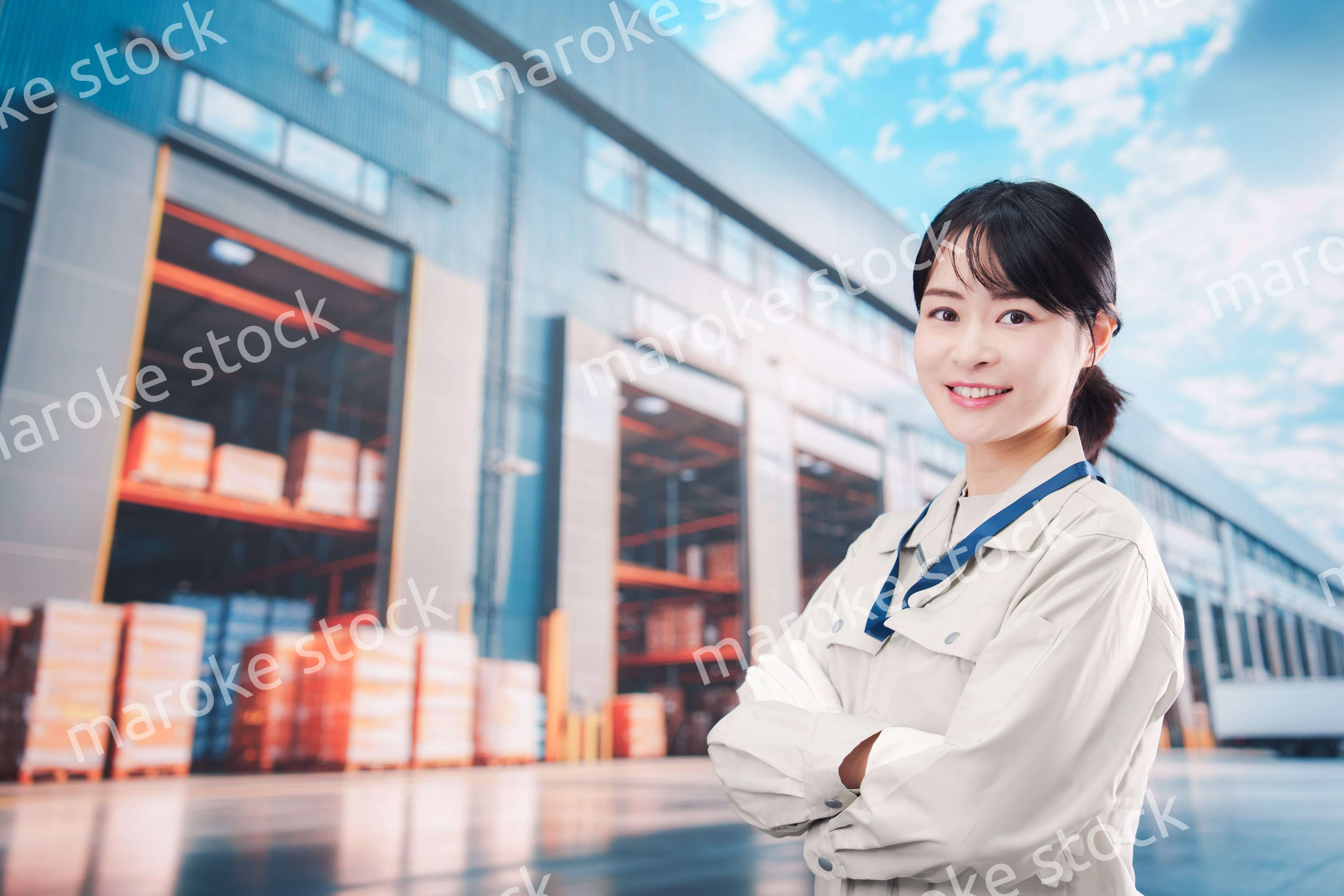 物流拠点で働く作業服姿の若い女性