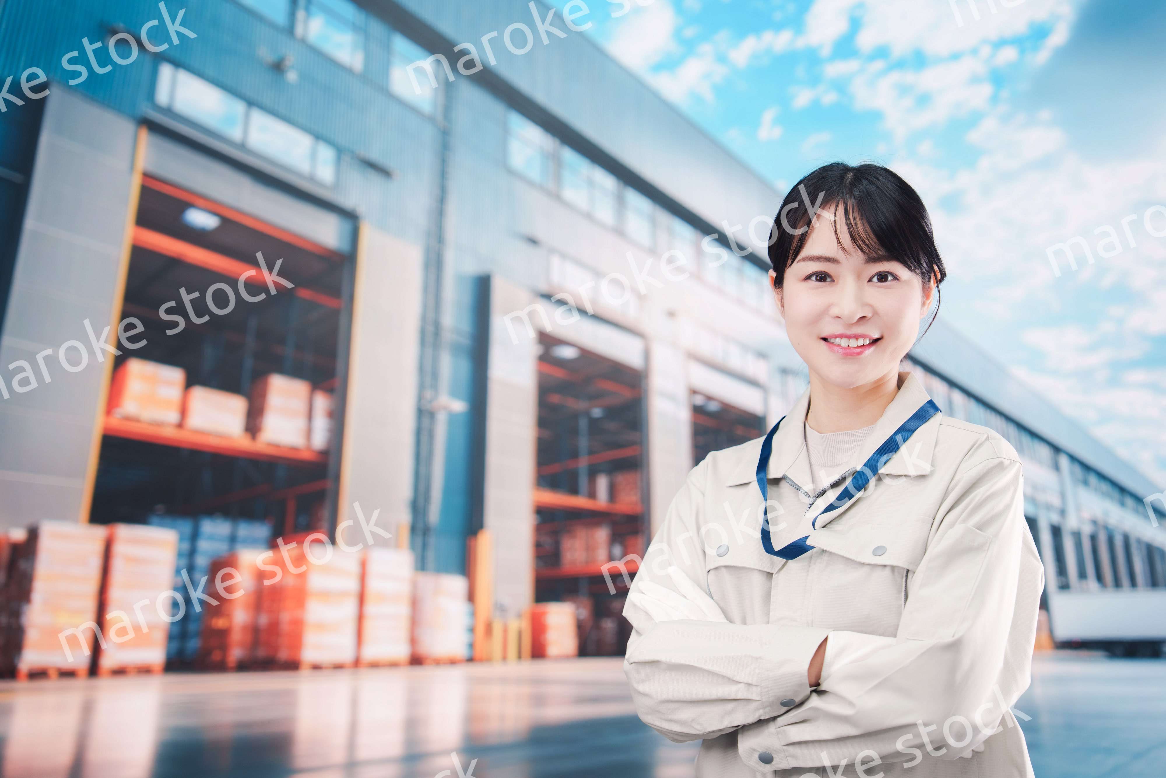 物流拠点で働く作業服姿の若い女性